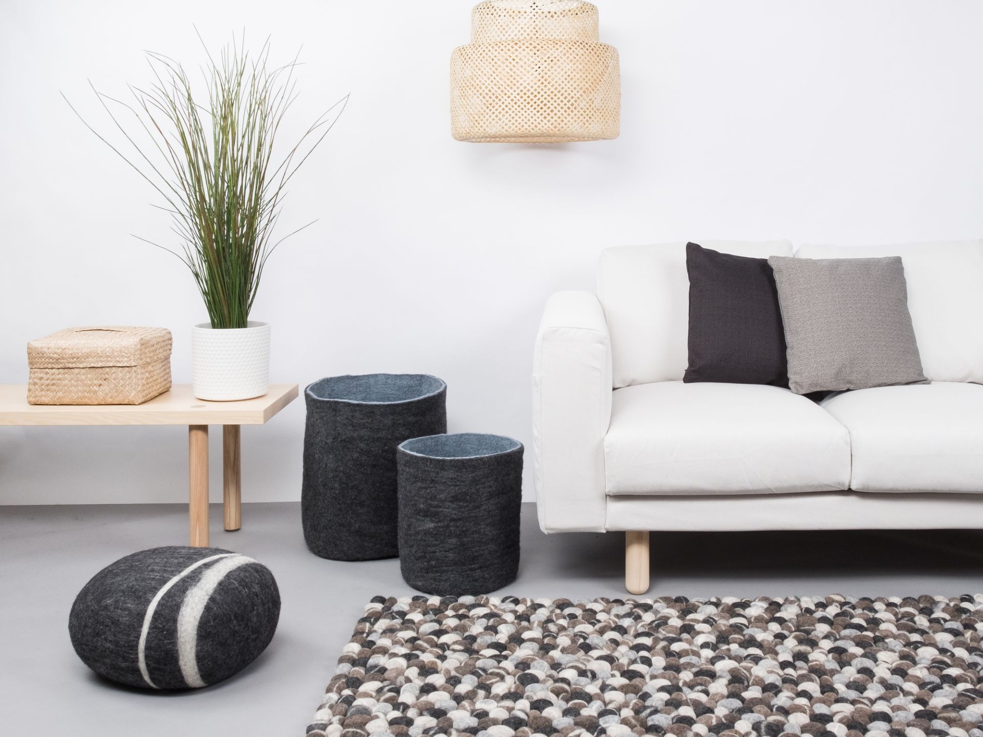 Handgefertigter myfelt Filzkugel Teppich in Grau- und Naturtönen, stilvolles Wohnzimmer-Ambiente mit Sofa und Dekoration.