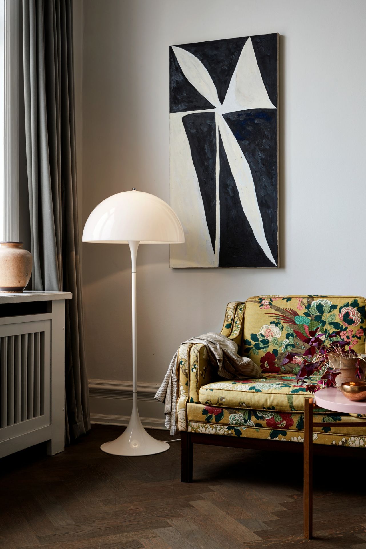 Weiße Panthella Stehleuchte von Louis Poulsen im Wohnzimmer mit Sessel und Kunstwerk.