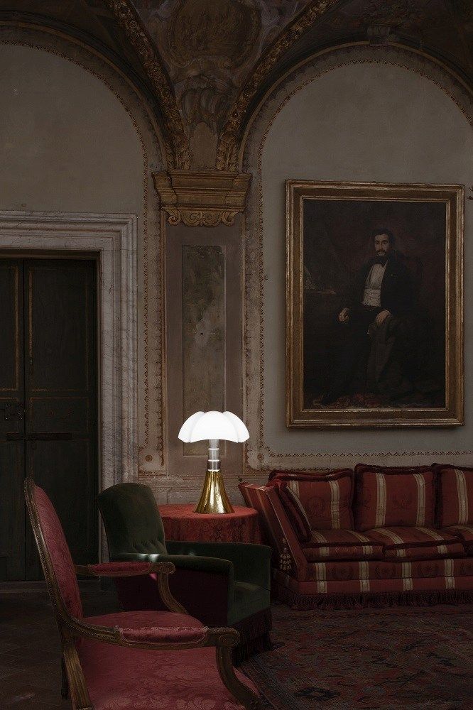 Pipistrello Tischleuchte von Martinelli Luce auf rotem Tisch in klassischem Interieur mit Sofa und Gemälde.