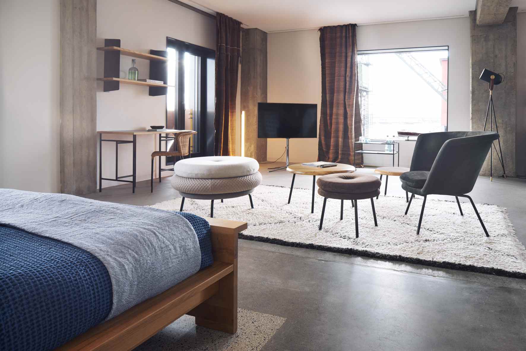 Wohnzimmer mit Fat Tom Pouf Hocker, grüner Sitzgelegenheit und modernem Interieur.