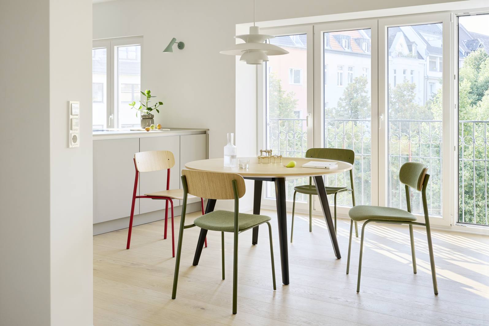 Esszimmer mit Thonet S 243 Stahlrohrstühlen in Olivgrün und Holztisch vor Fensterfront.