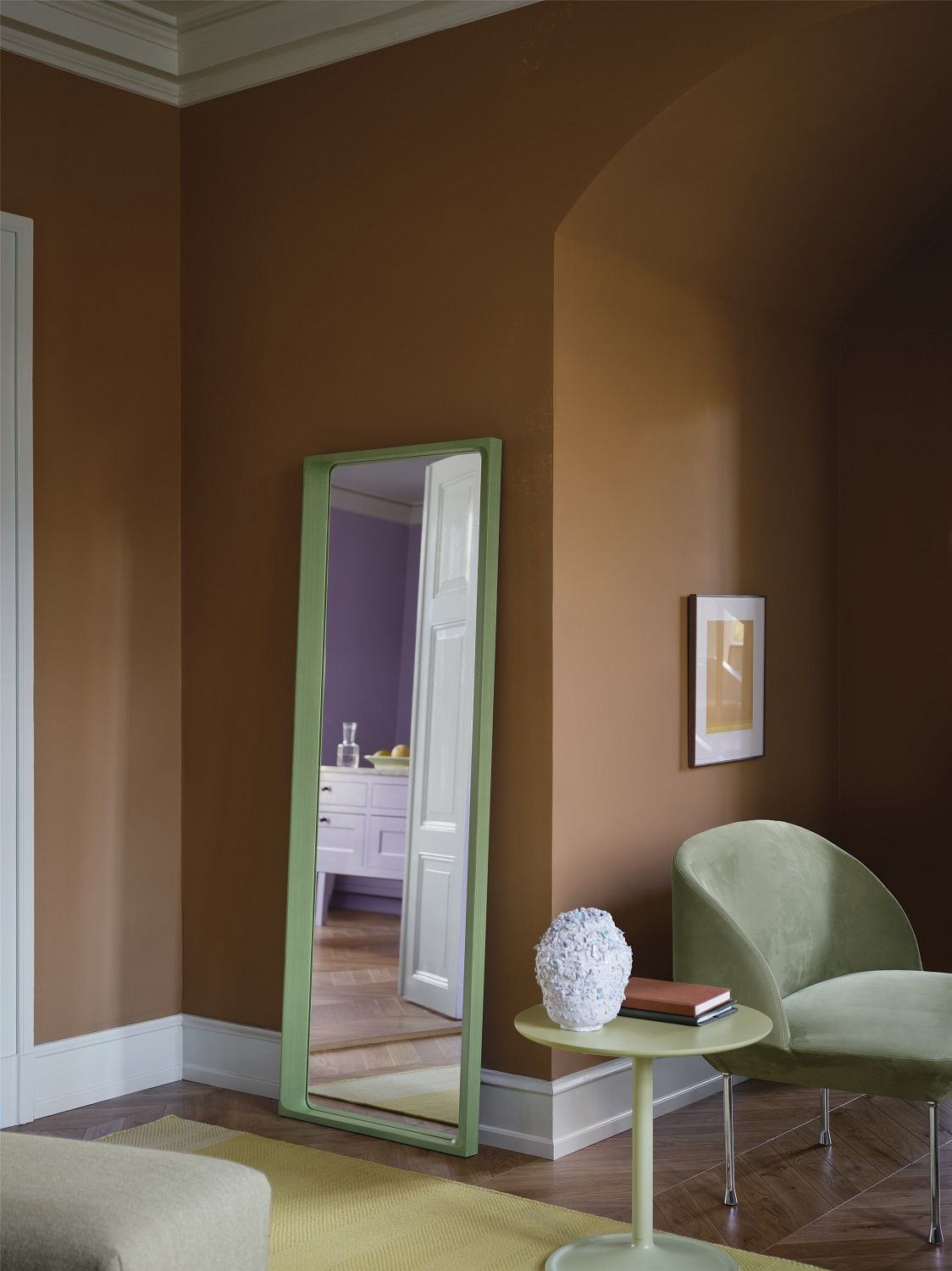 Arced Mirror von Muuto, ein schlanker, rechteckiger Spiegel mit hellgrünem Rahmen in modernem Wohnzimmer.