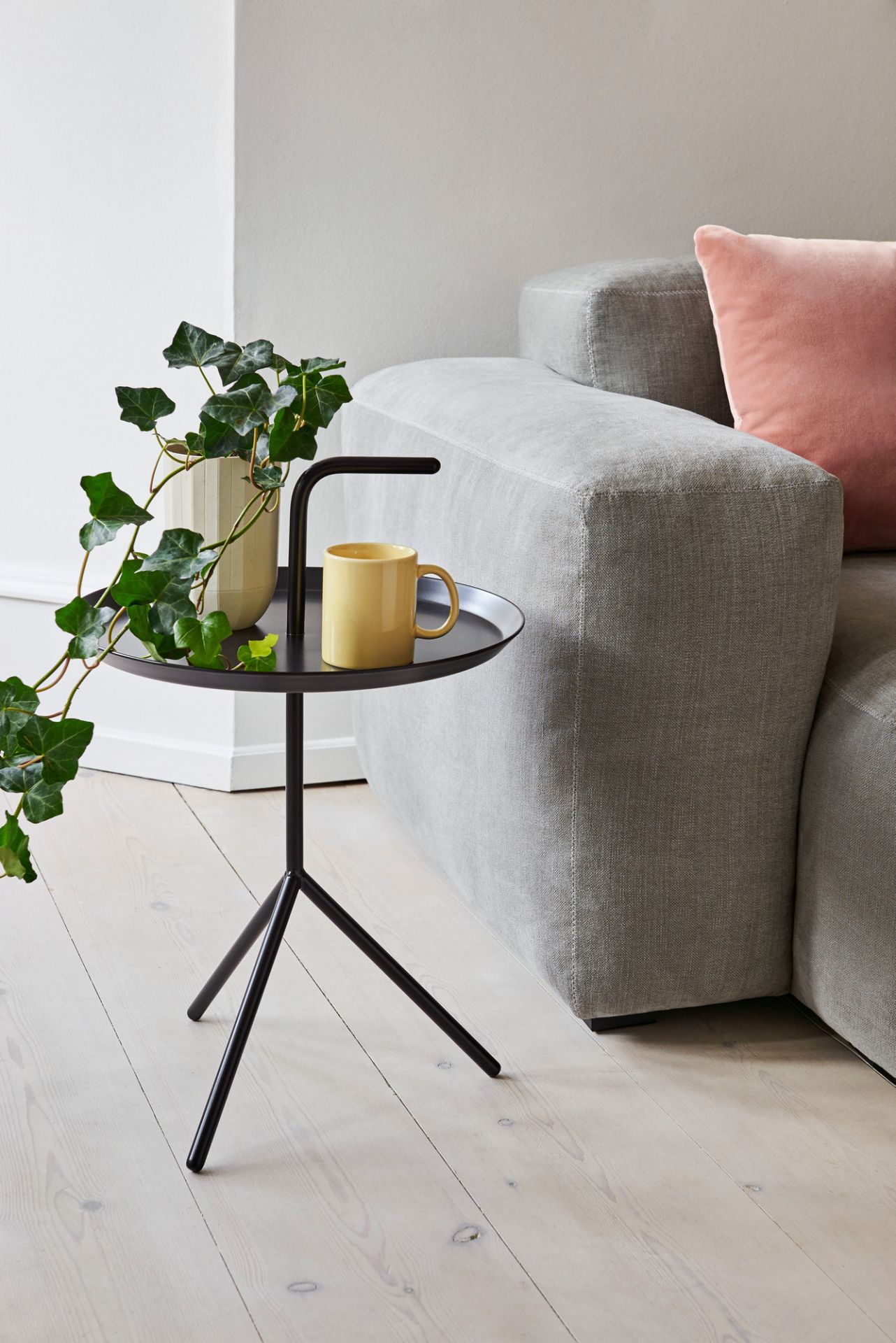 Detailaufnahme vom Hay Mags Sofa in Grau mit Beistelltisch, Pflanze und gelber Tasse.