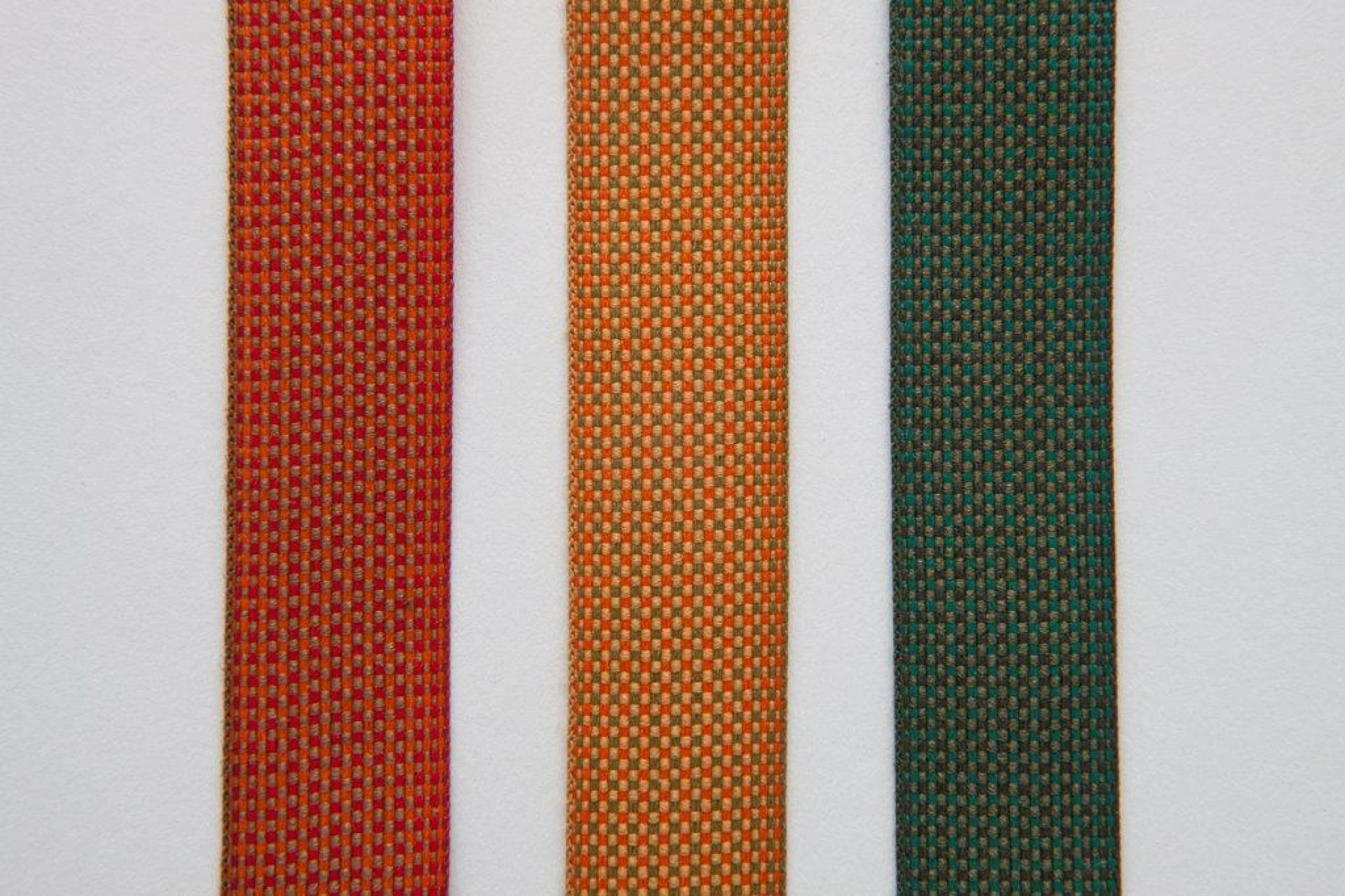 Nahaufnahme von drei Stoffstreifen in Rot, Orange und Grün.