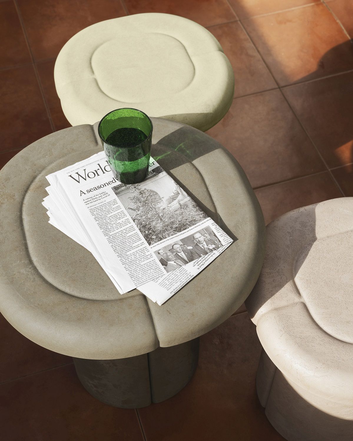 Nahaufnahme von Mater Alder Beistelltisch im Außenbereich mit Zeitung und grünem Glas, moderne Gartentische.