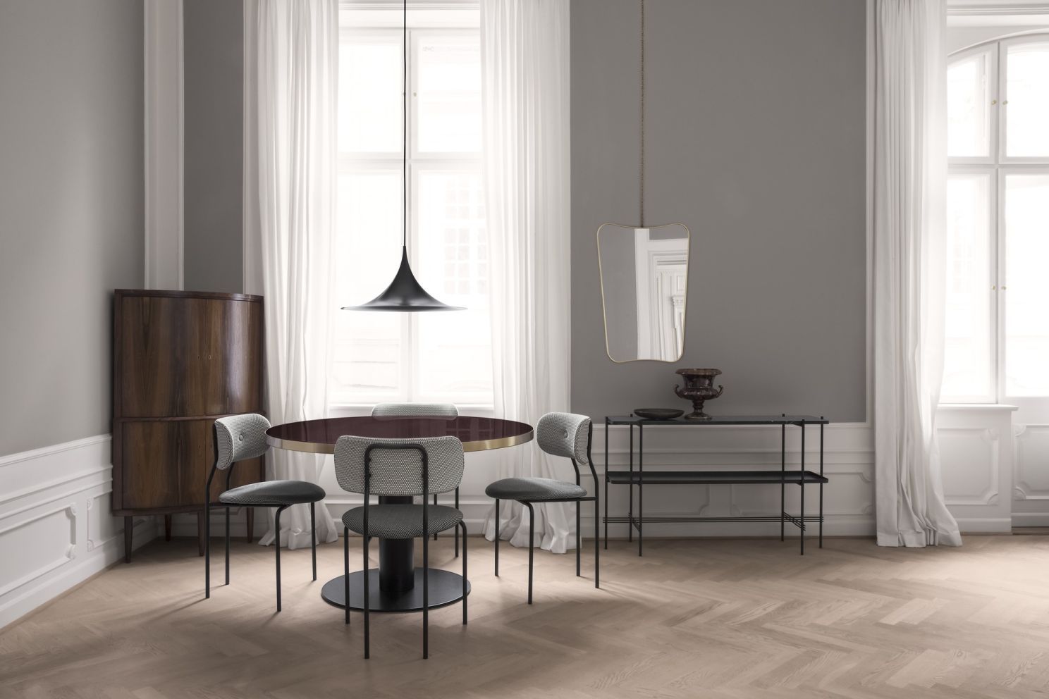 F.A. 33 Wandspiegel von Gubi in einem Esszimmer mit Tisch und Stühlen.