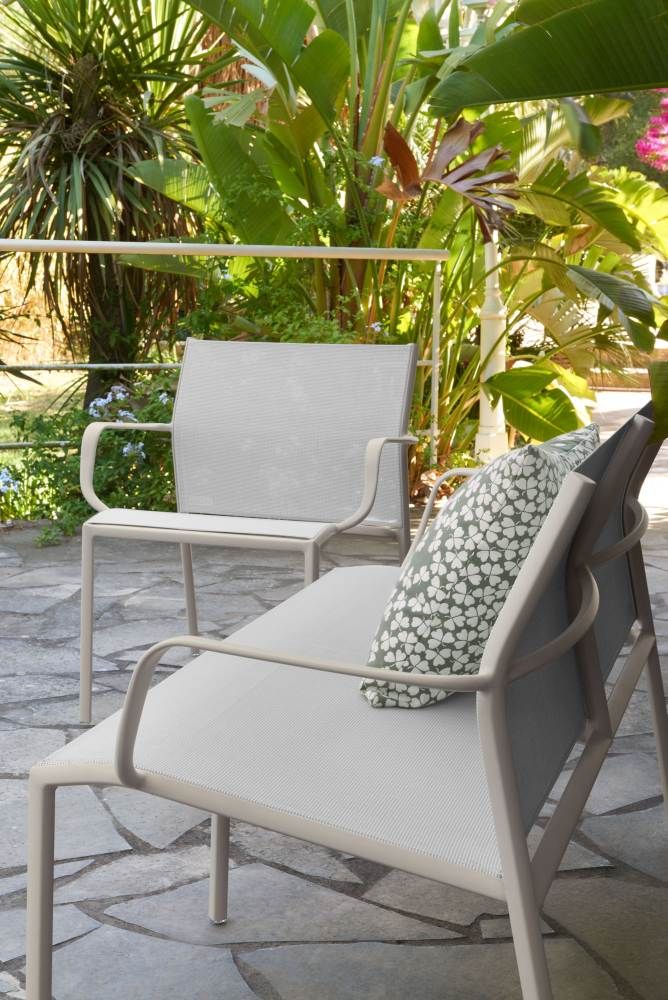 Nahaufnahme der grauen Cadiz Gartenbank von Fermob mit Kissen und passendem Stuhl.