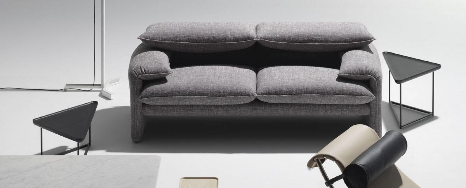 Graues Cassina Maralunga Sofa, Zweisitzer, modernes Design mit bequemen Kissen und minimalistischen Beistelltischen.