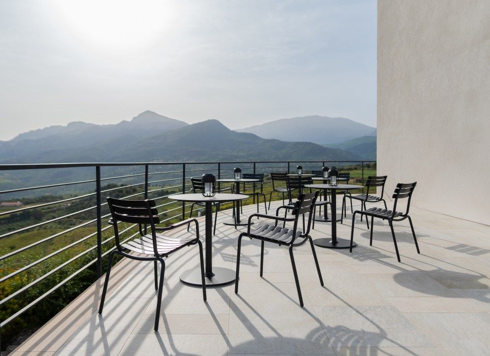Alua Armrest Dining Chair von Houe auf einer Terrasse mit Bergblick. Outdoor Stuhl.