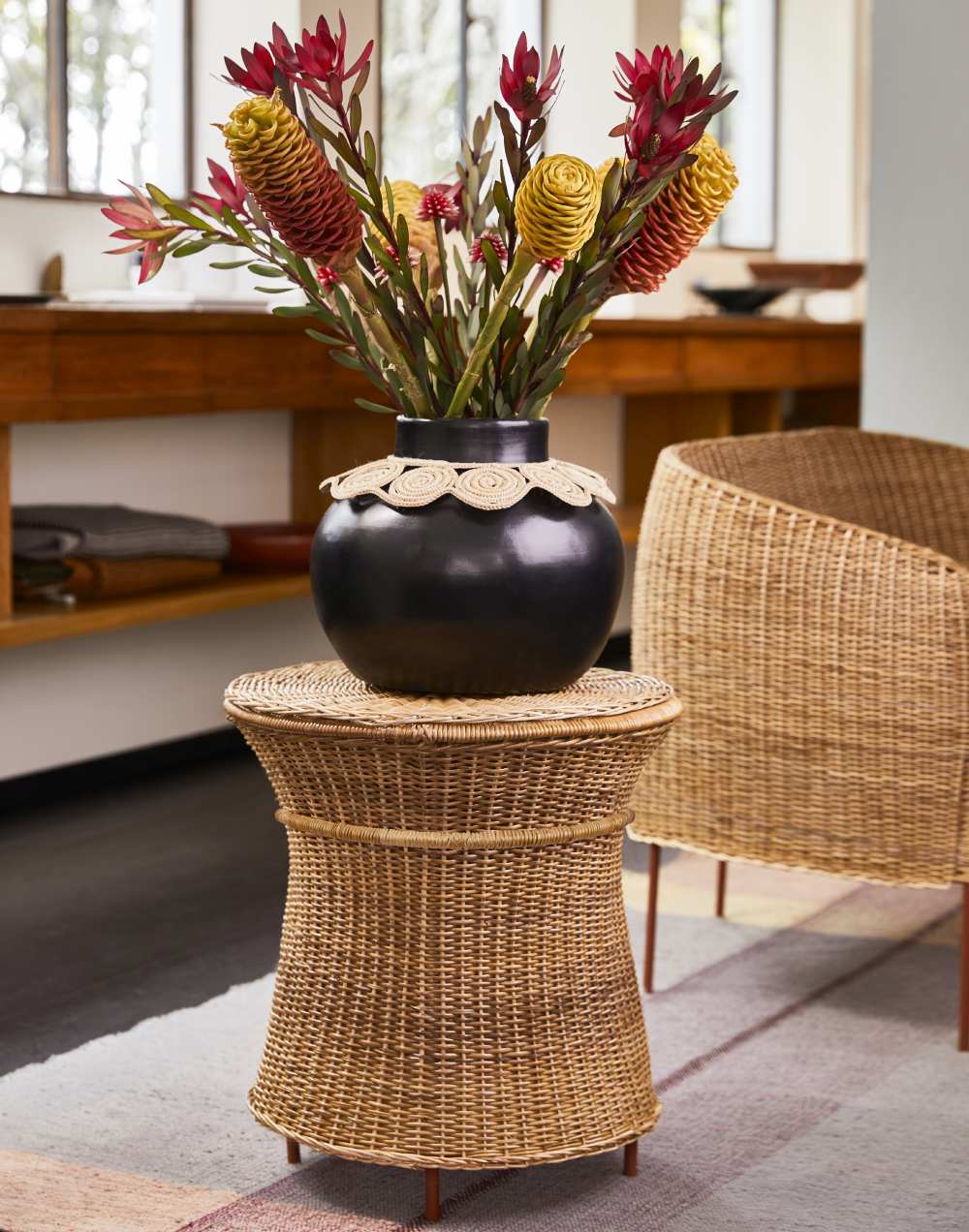 Caribe Natural Beistelltisch von ames: Rattan Outdoor Tisch mit Blumenvase im Wohnzimmer.