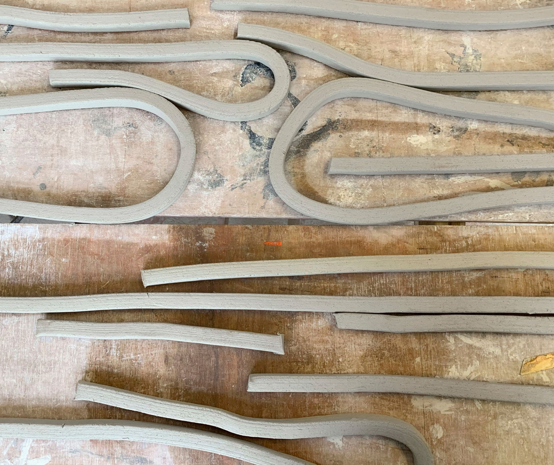 Nahaufnahme von Tonstreifen für Vitra Découpage Vasen, handgefertigte Keramik, DIY-Töpferkunst auf Holztisch.