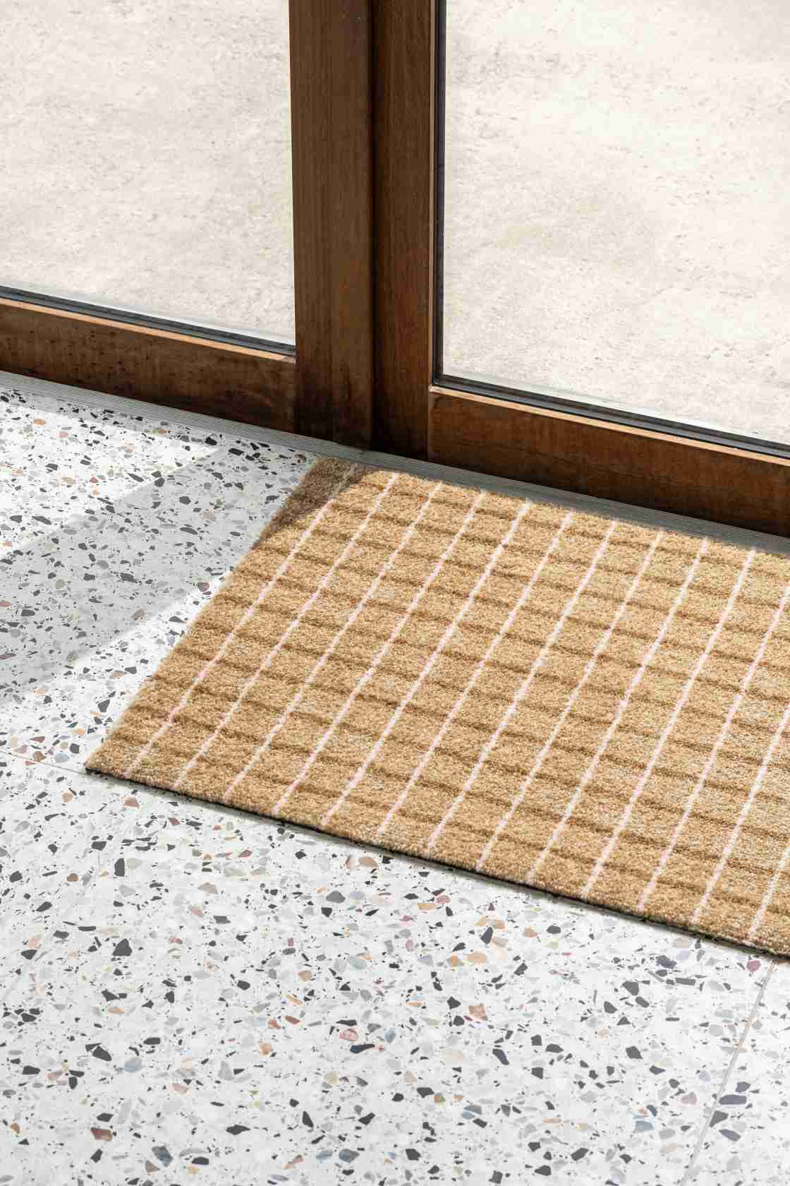 Grid Indoor Fußmatte in Schoko-Erdbeer Optik vor einer Tür. Robuste Fußmatte für den Innenbereich.