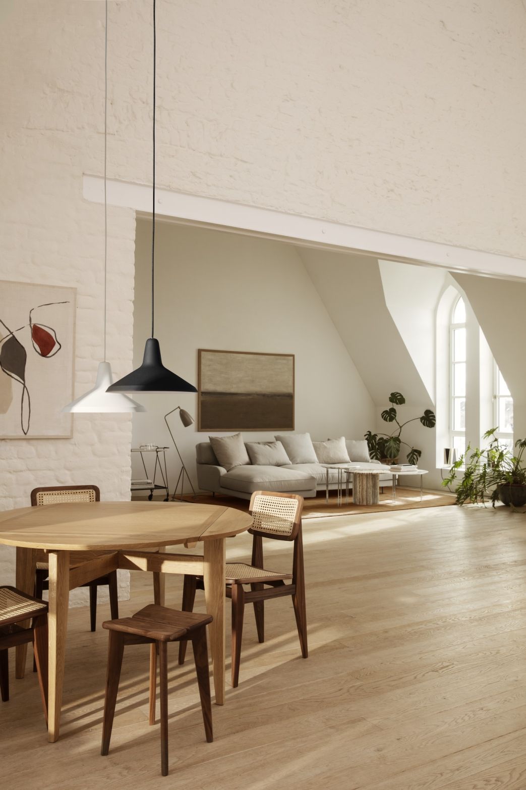 Heller Wohnraum mit Gubi B-Table Esstisch aus Holz, Stühlen mit Wiener Geflecht und Pendelleuchten.