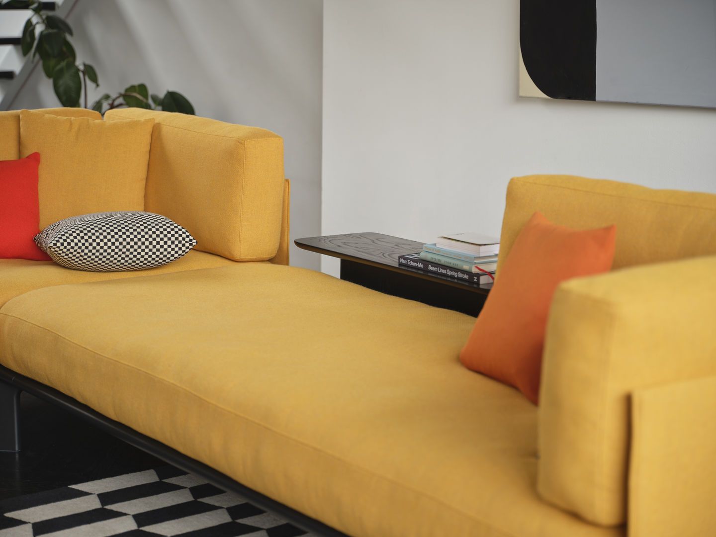 Nahaufnahme eines gelben Anagram Sofas von Vitra mit Kissen und Beistelltisch im Wohnzimmer.