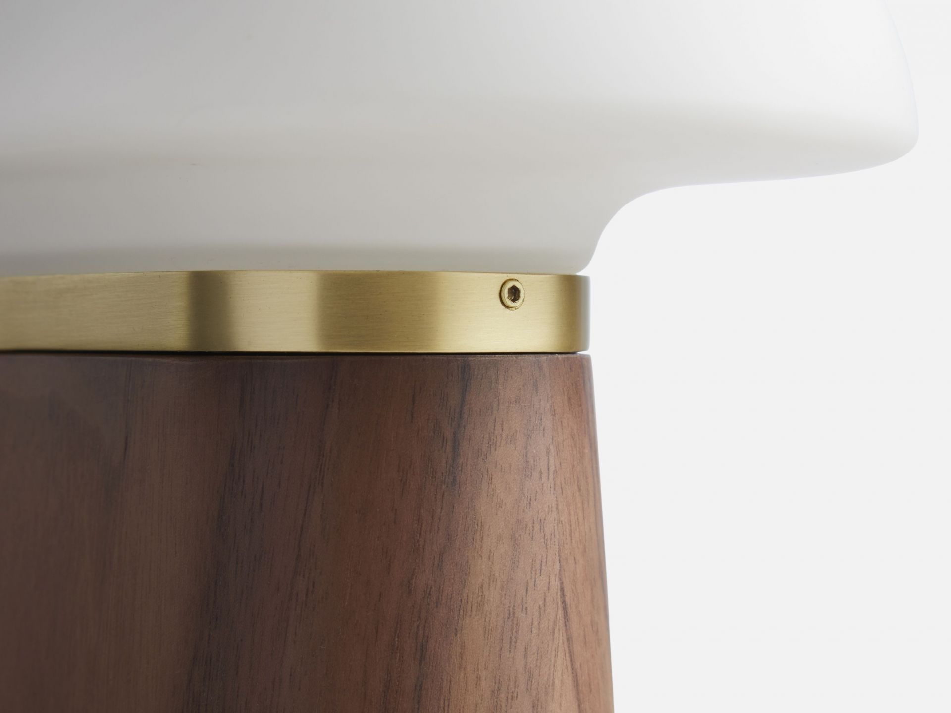 Detailaufnahme der Nova Tischleuchte von Woud mit Walnuss-Holzfuß und Messingdetails.