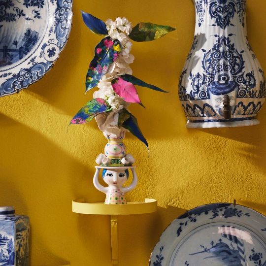 Lady with Hat Kerzenständer von Bjorn Wiinblad, dekorative Wohnaccessoires auf gelber Wand mit Blumen.