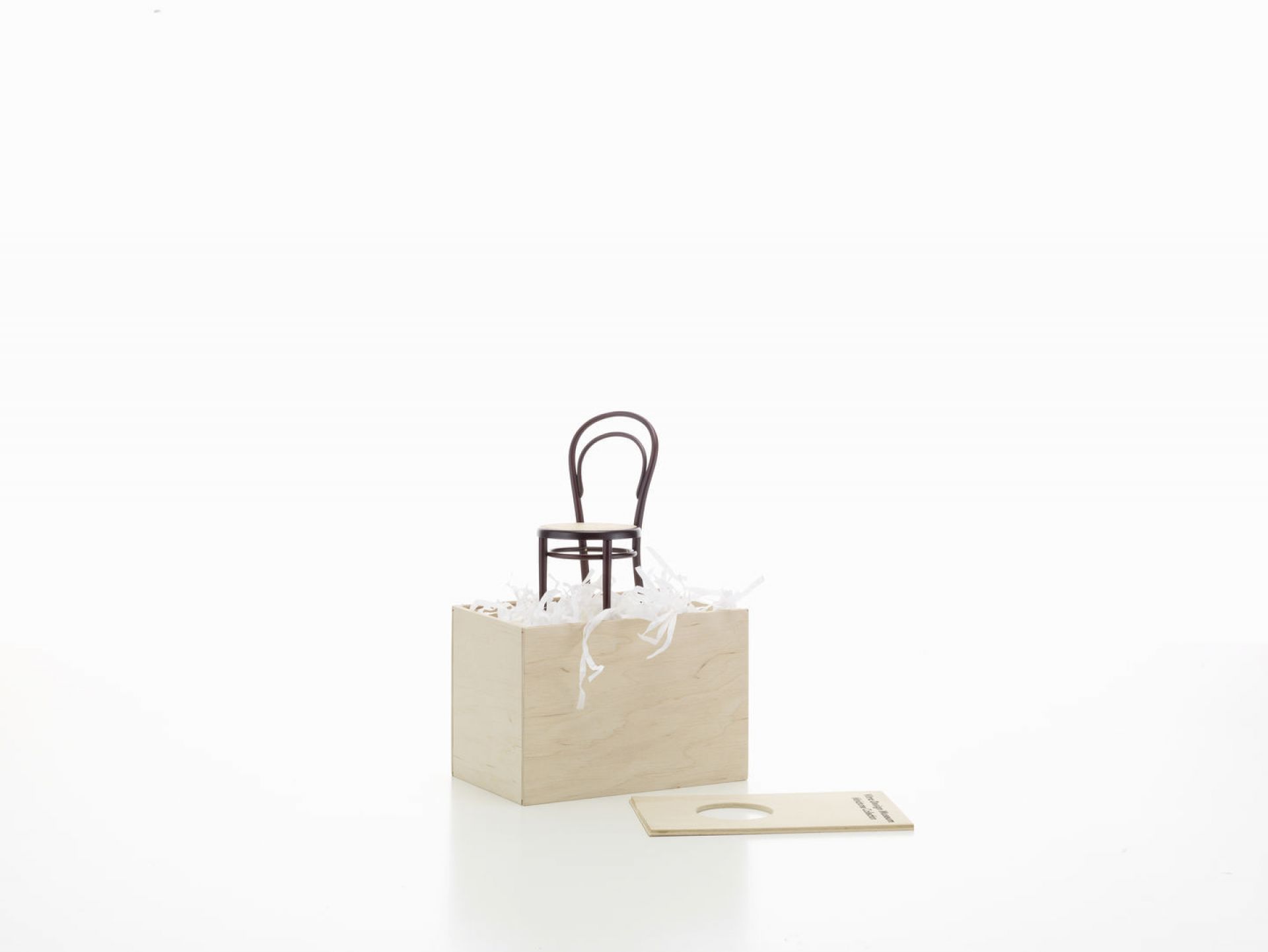 Miniatur Stuhl No. 14 von Vitra auf einer Holzbox mit Füllmaterial. Designklassiker.
