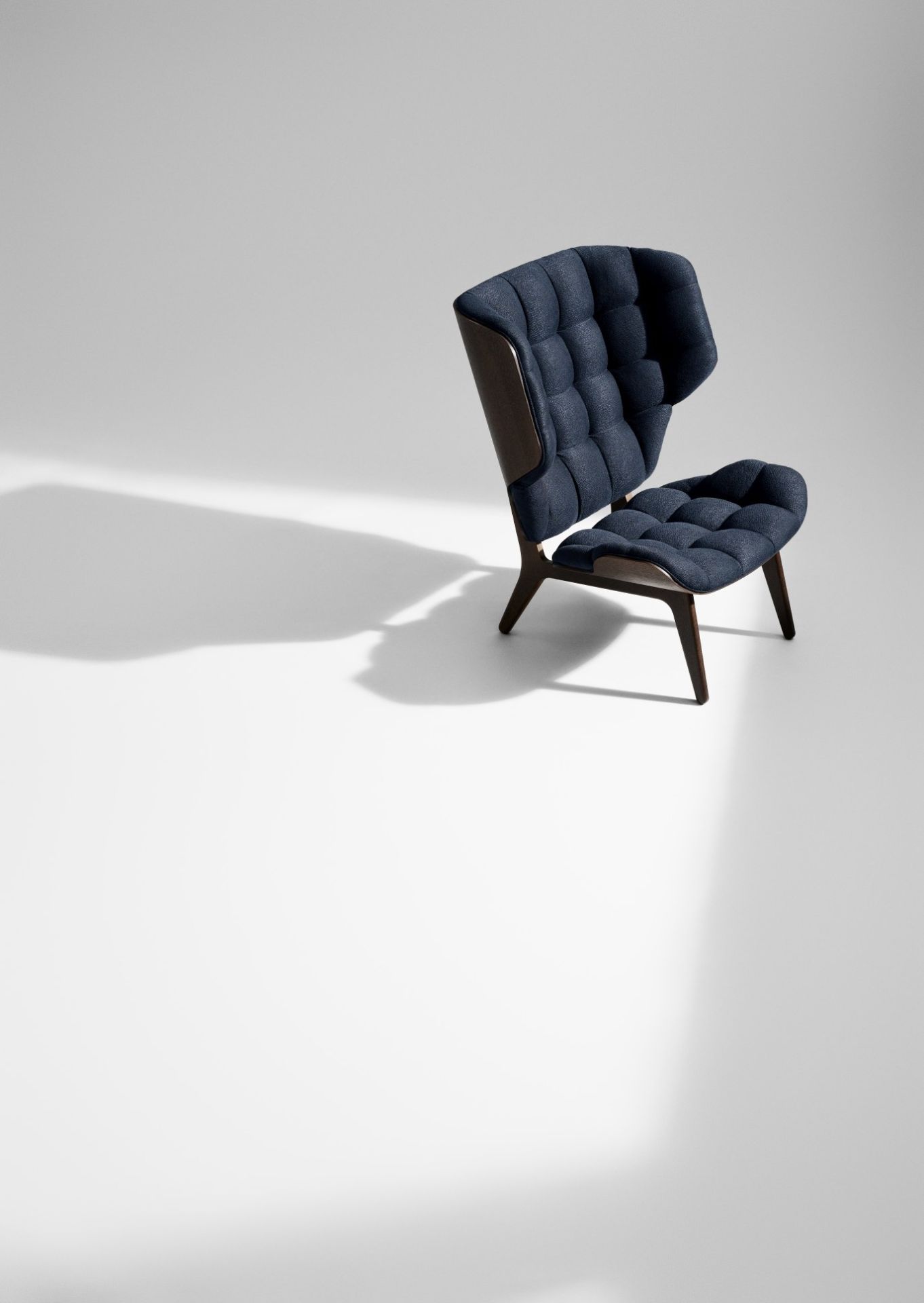 NORR11 Mammoth Chair Sessel mit dunkelblauem Polster und dunklem Holzrahmen auf weißem Hintergrund.