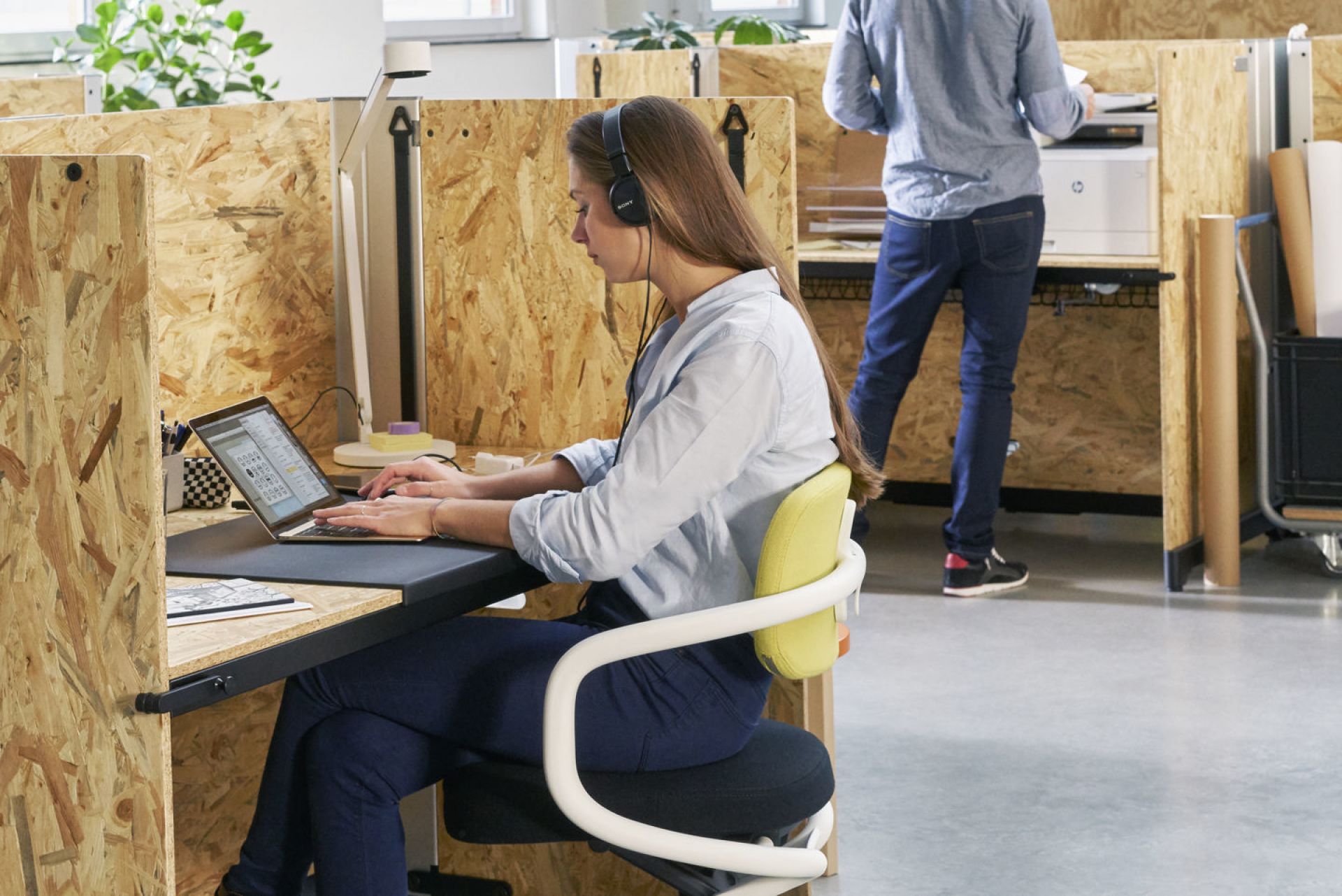 Frau arbeitet am Laptop auf einem Allstar Bürodrehstuhl von Vitra mit gelber Rückenlehne im Büro.