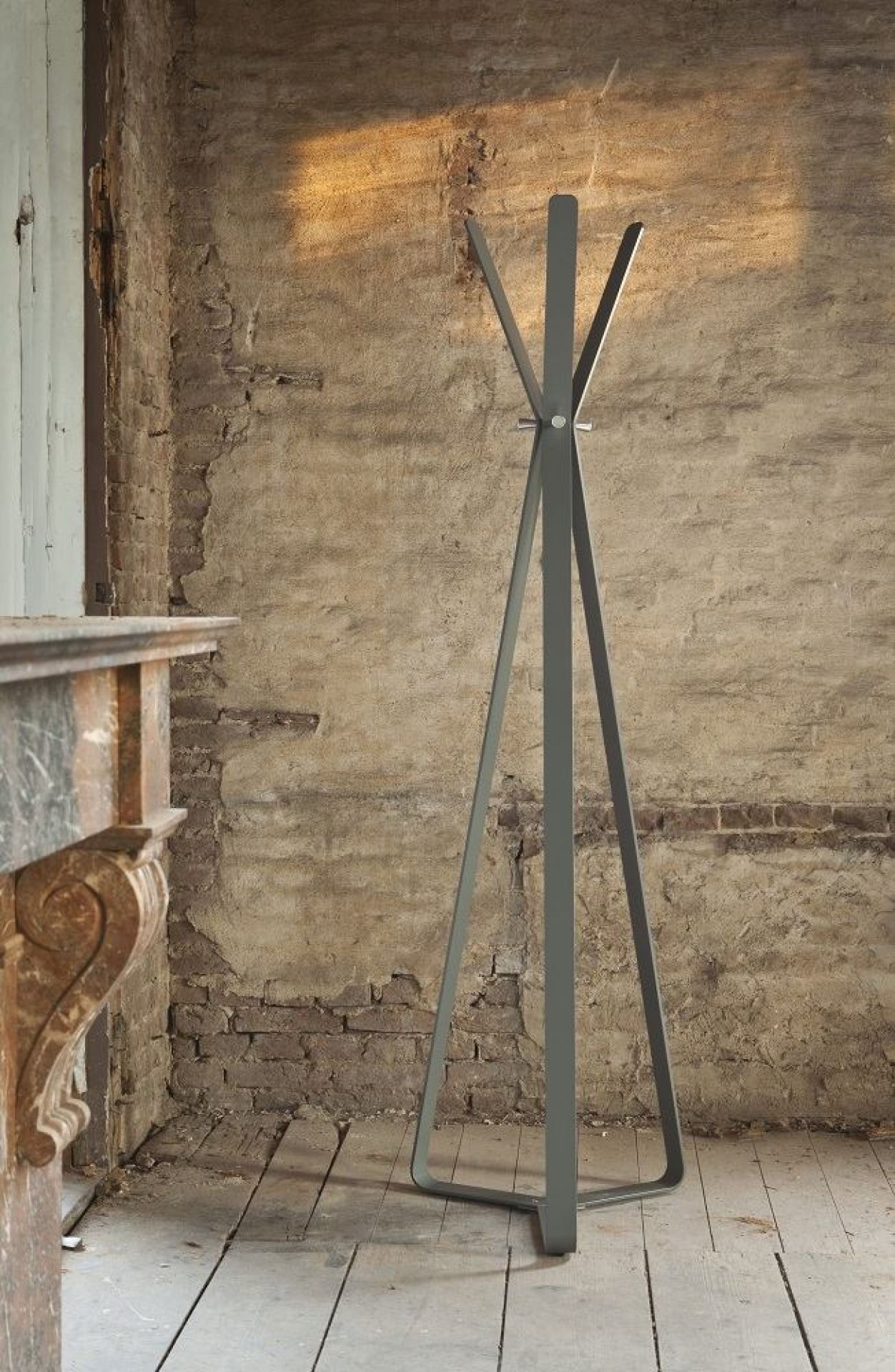 Graue, moderne Garderobe aus Metall vor einer rustikalen Ziegelwand und Holzboden im Innenraum.