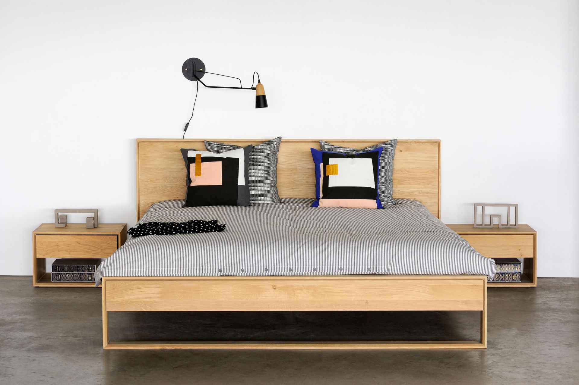 Nordic II Nachttisch von Ethnicraft aus Eiche neben einem Bett mit Nachttischlampe.