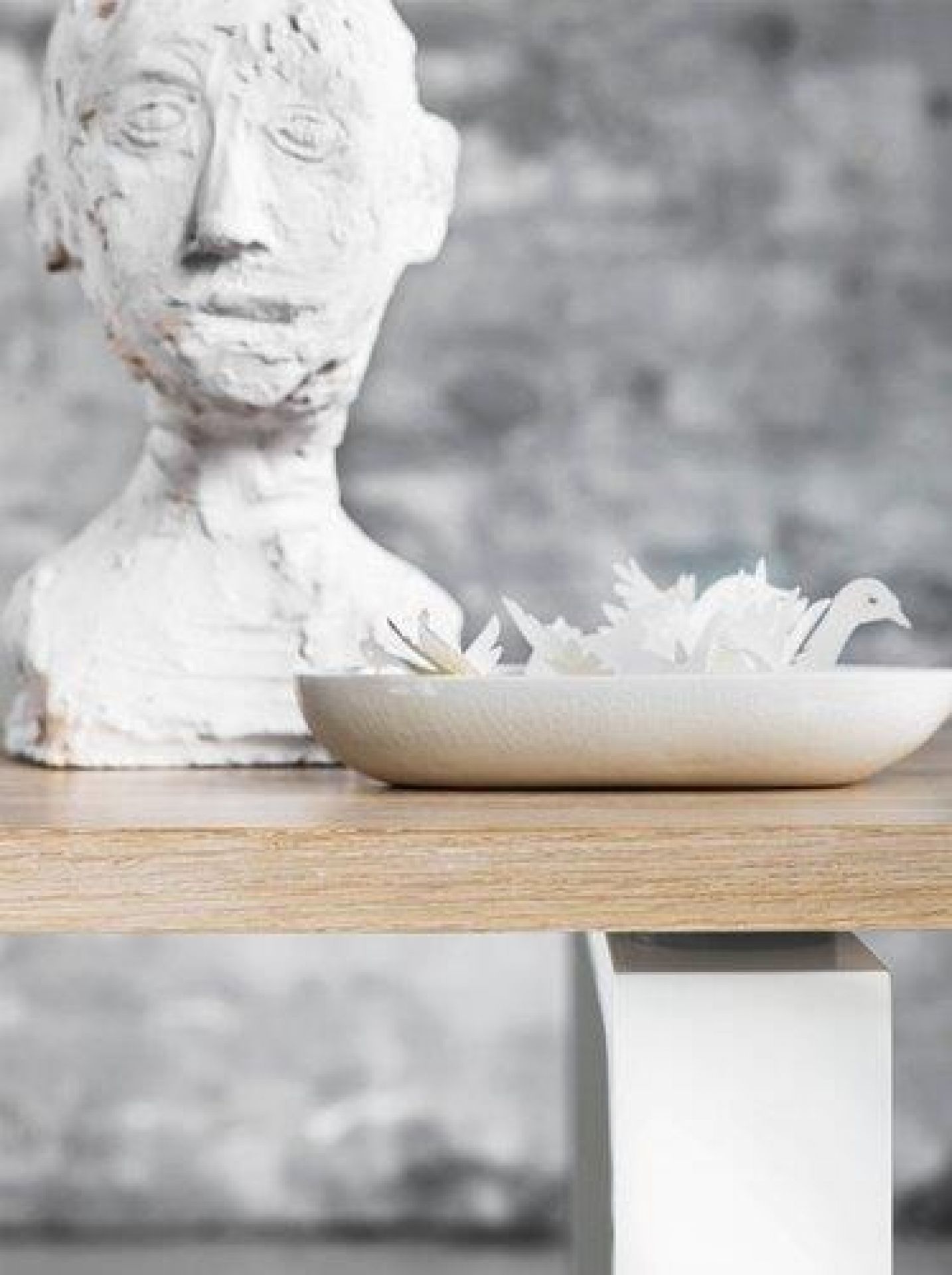 Detailaufnahme vom Fritz Hansen Essay Tisch mit Eichenplatte und weißem Untergestell, dekoriert mit Skulptur und Schale.