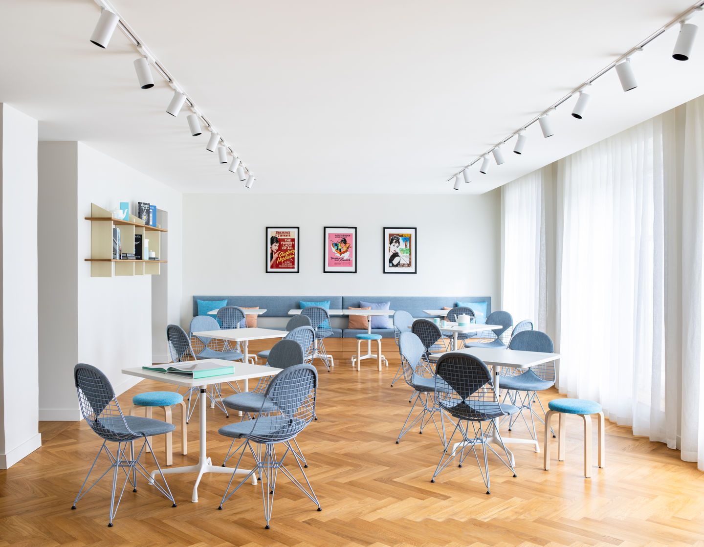 Heller Raum mit mehreren DKR Wire Chairs von Vitra mit Sitzpolster an weißen Tischen.