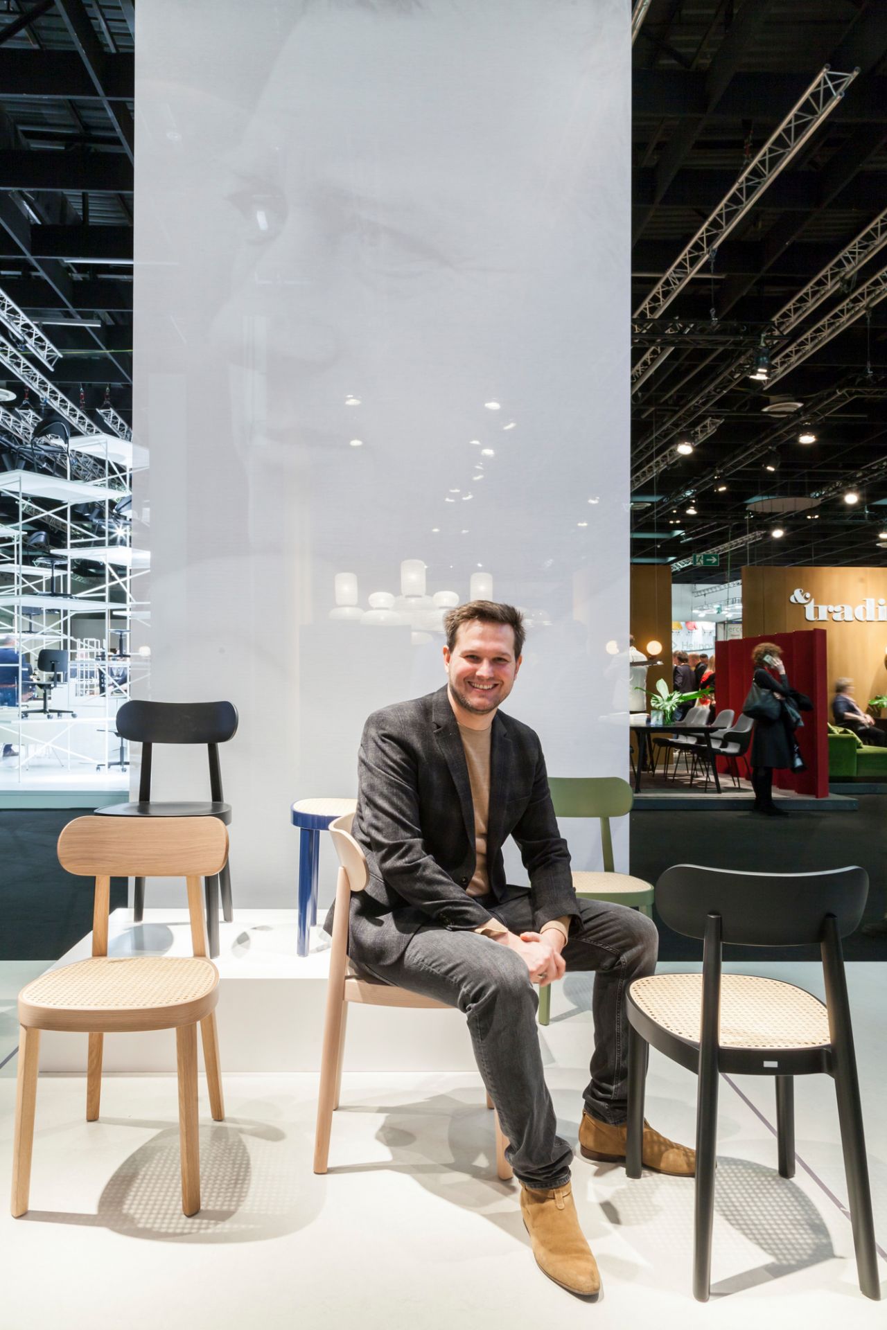 Mann sitzt auf einem Thonet Holzstuhl 118 M. Designklassiker mit Wiener Geflecht. Nussbaumholz.