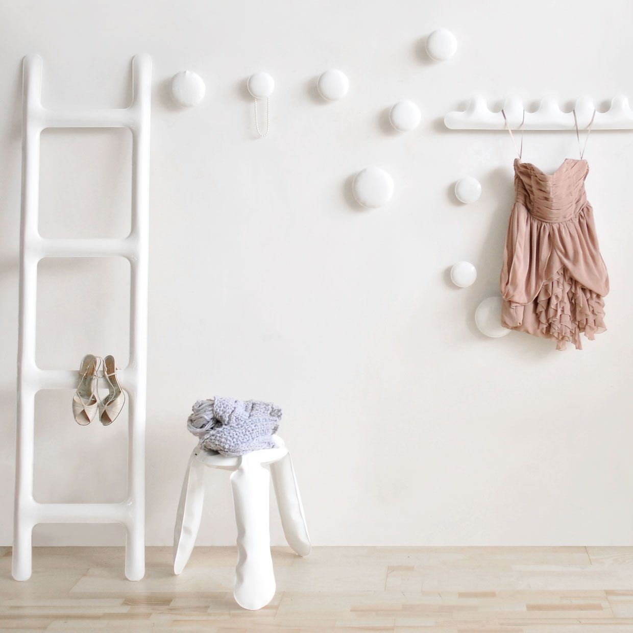 Weiße Kamm Garderobe von Zieta mit Kleidern, Schuhen und Hocker an einer weißen Wand.