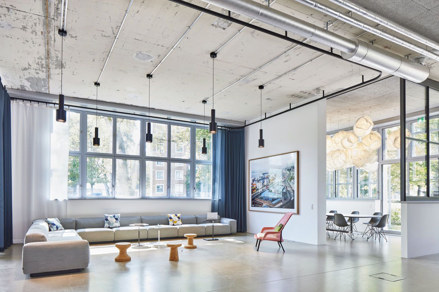 Heller Raum mit Vitra Slow Chair Sessel in Rosa und Ottoman, grauer Couch und Fensterfront.