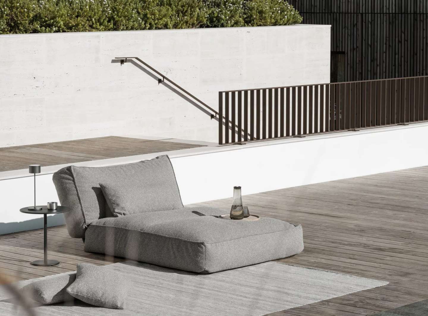 Graues Blomus Reah Sun Outdoor Kissen 80x40 cm auf einer Terrasse mit Holzboden.
