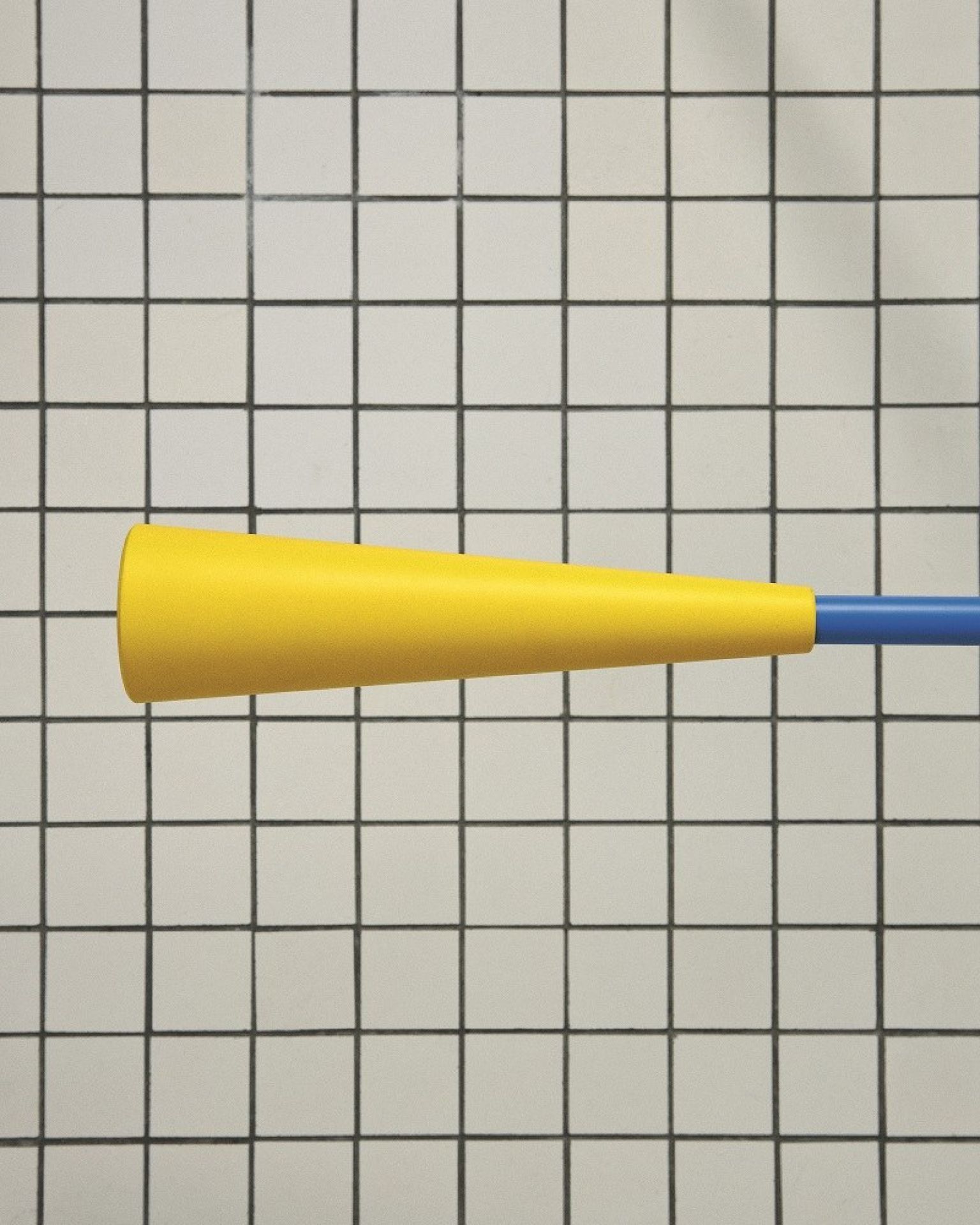 Nahaufnahme der Flos 265 Chromatica Wandleuchte mit gelbem Lampenschirm und blauem Arm vor Fliesenhintergrund.