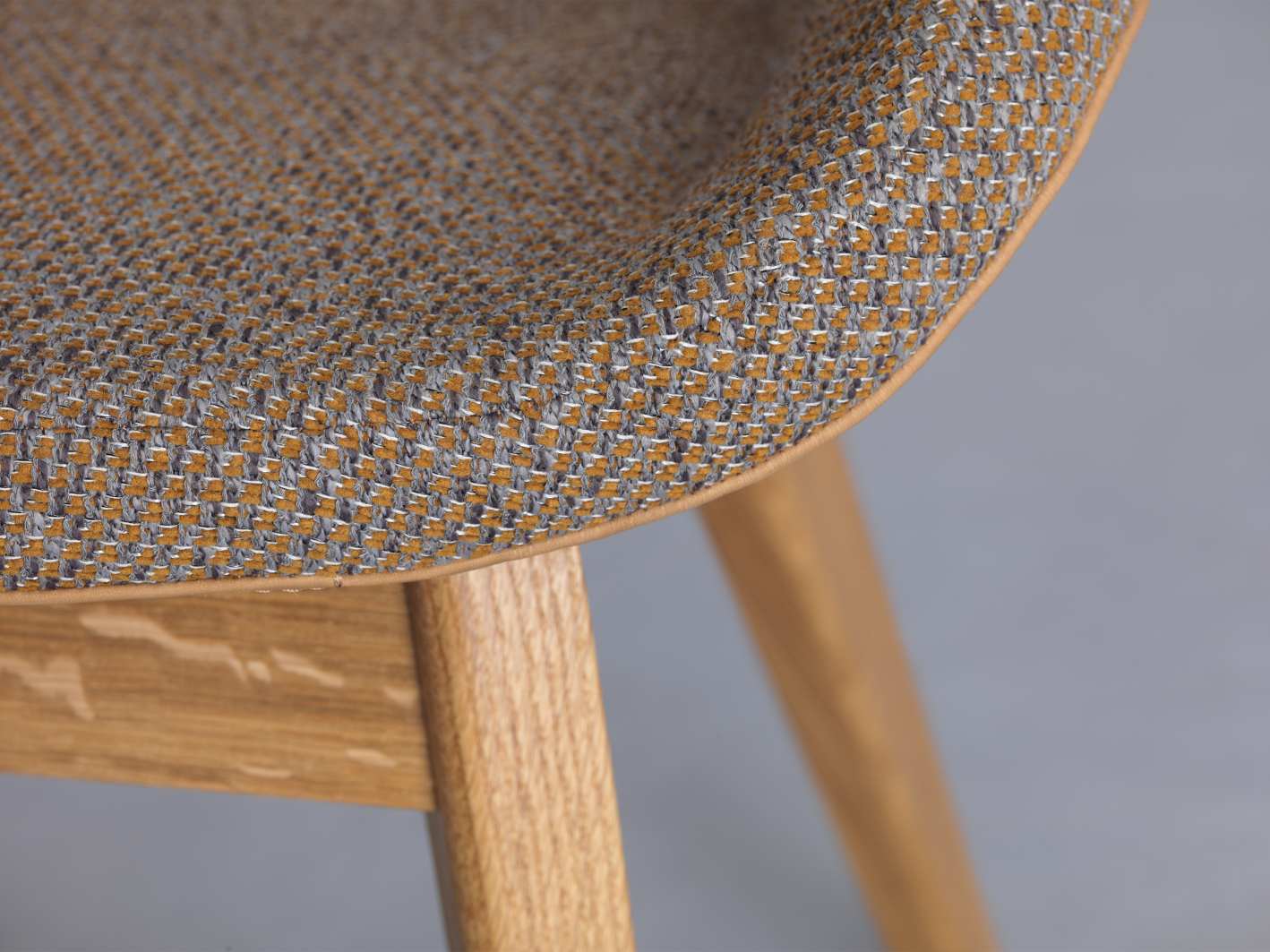 Detailaufnahme des Morph Dining Chair Stuhls mit gelb-grauem Webstoff und hellem Holzgestell.