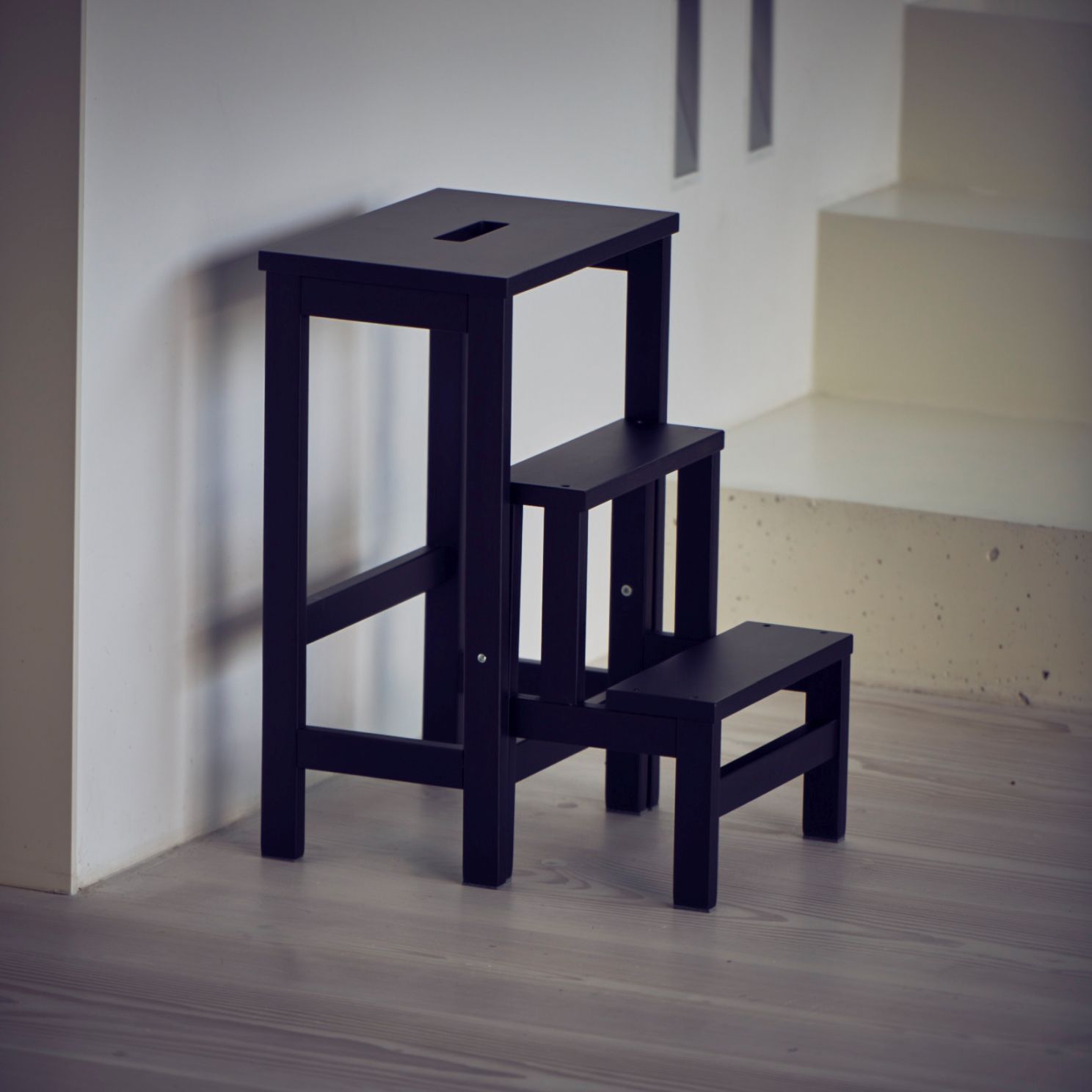 Soho Hockerleiter von Jan Kurtz, schwarzer Tritthocker aus Holz mit drei Stufen, seitliche Ansicht.