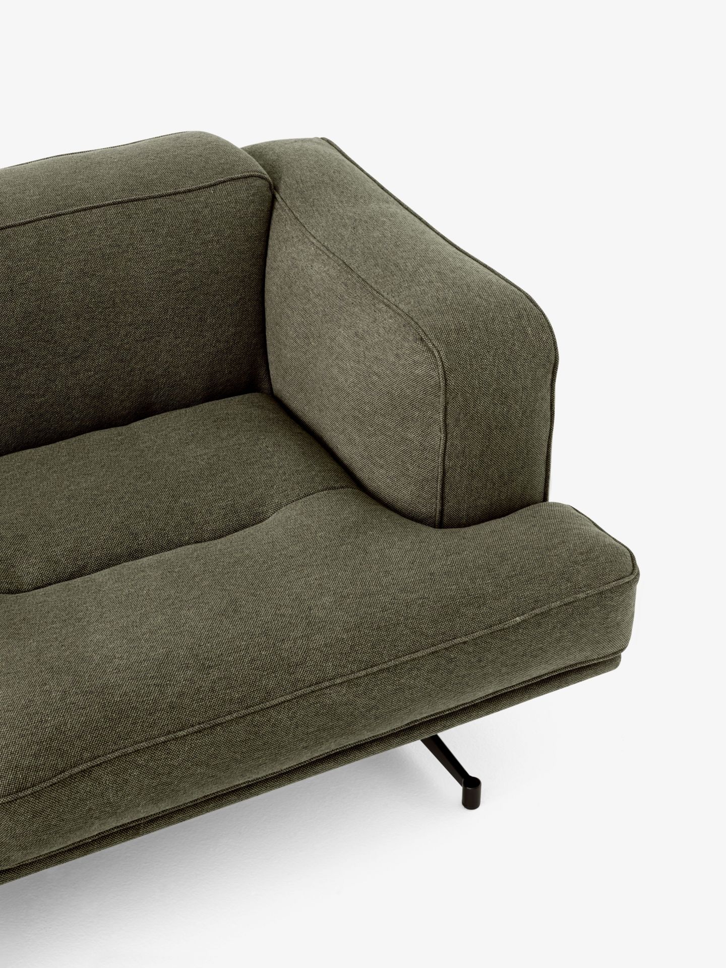 Detailaufnahme des Inland AV22 Sofas von AndTradition in Olivgrün mit minimalistischem Design und schwarzen Metallfüßen.