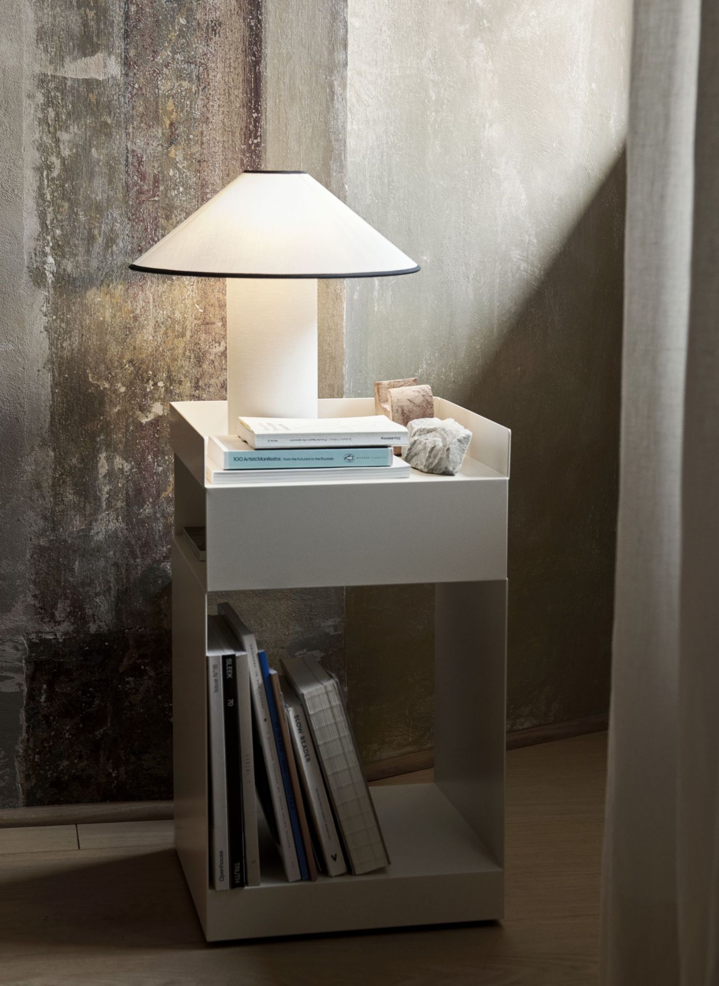 AndTradition Colette Tischleuchte ATD6 auf weißem Nachttisch mit Büchern und Dekoration. Moderne Tischlampe für Schlafzimmer.