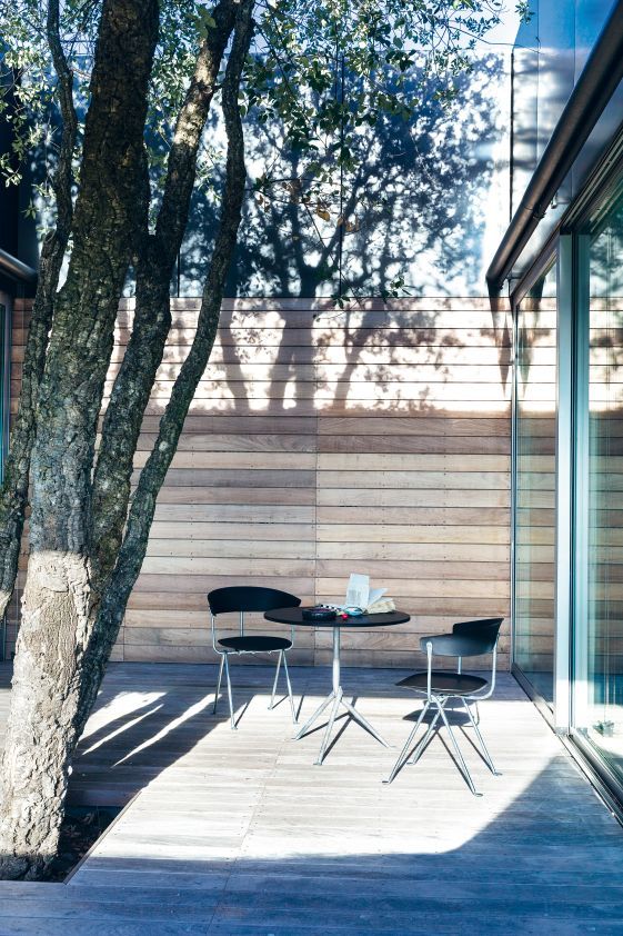 Zwei schwarze Magis Stühle mit Tisch auf einer Holzterrasse im Freien.