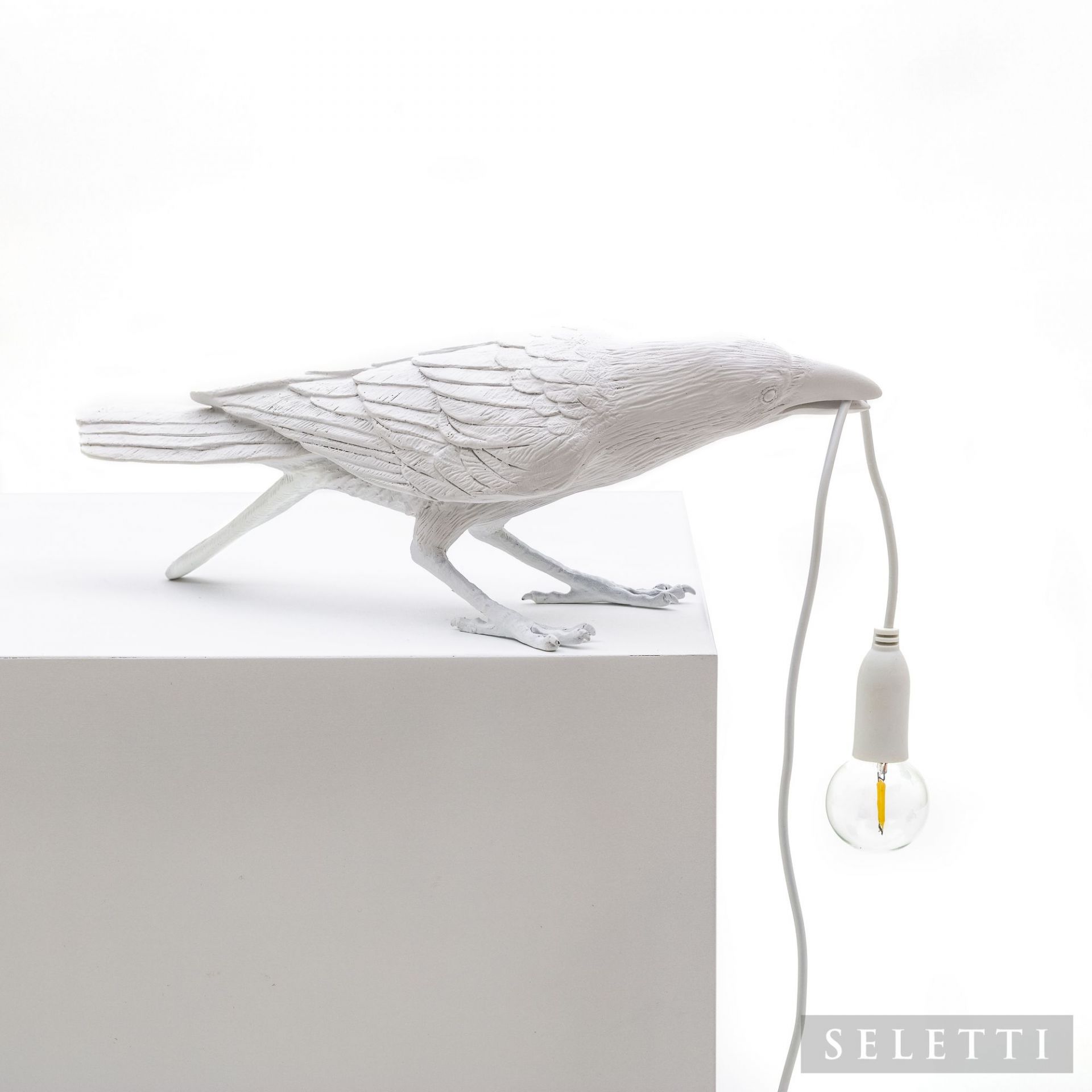 Weiße Bird Lamp Playing Leuchte von Seletti: Dekorative Tischleuchte in Form eines Raben mit Glühbirne im Schnabel.