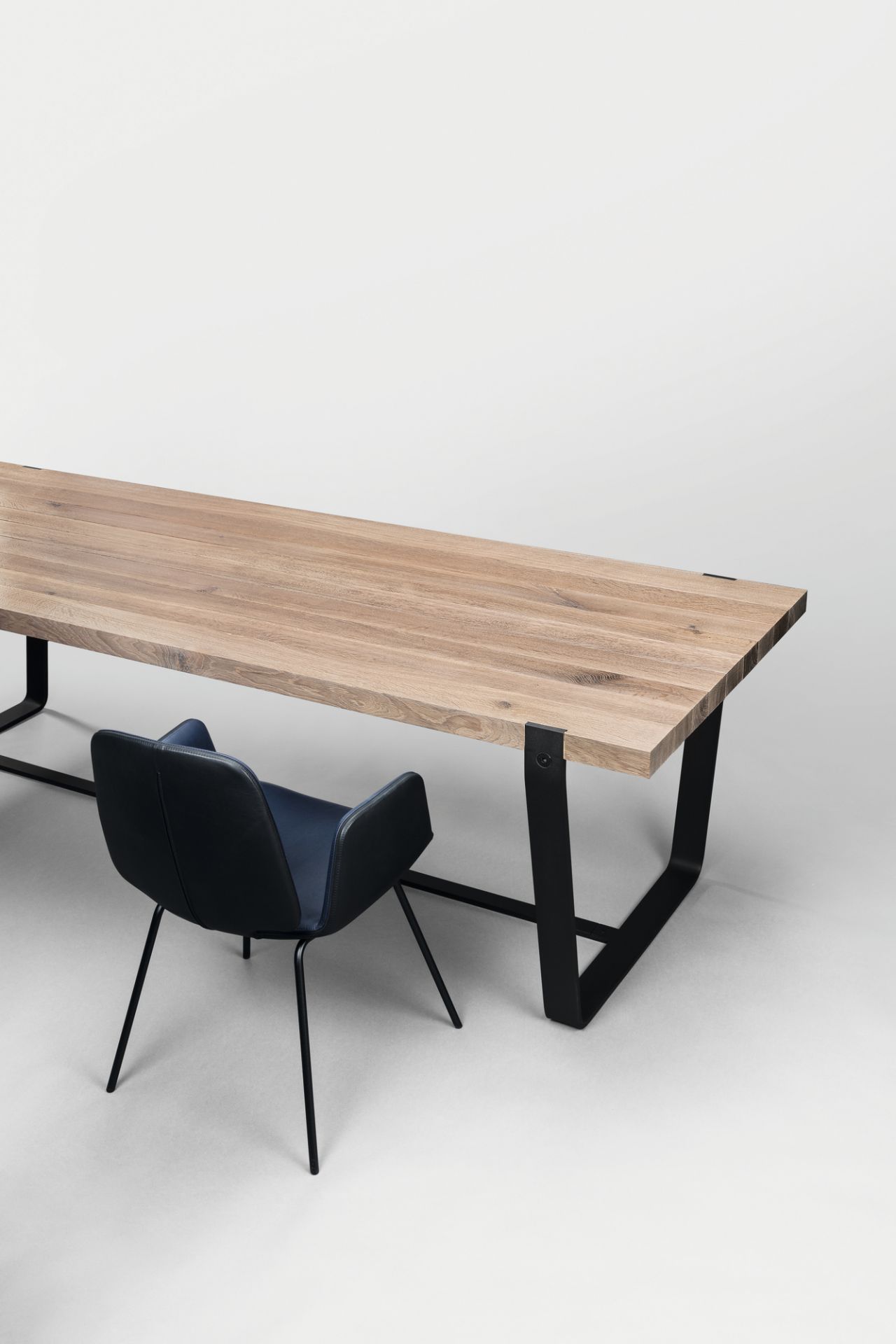 BB 11 Clamp Tisch Eiche Janua: Moderner Esstisch aus Eichenholz mit schwarzem Stahlgestell und Stuhl.