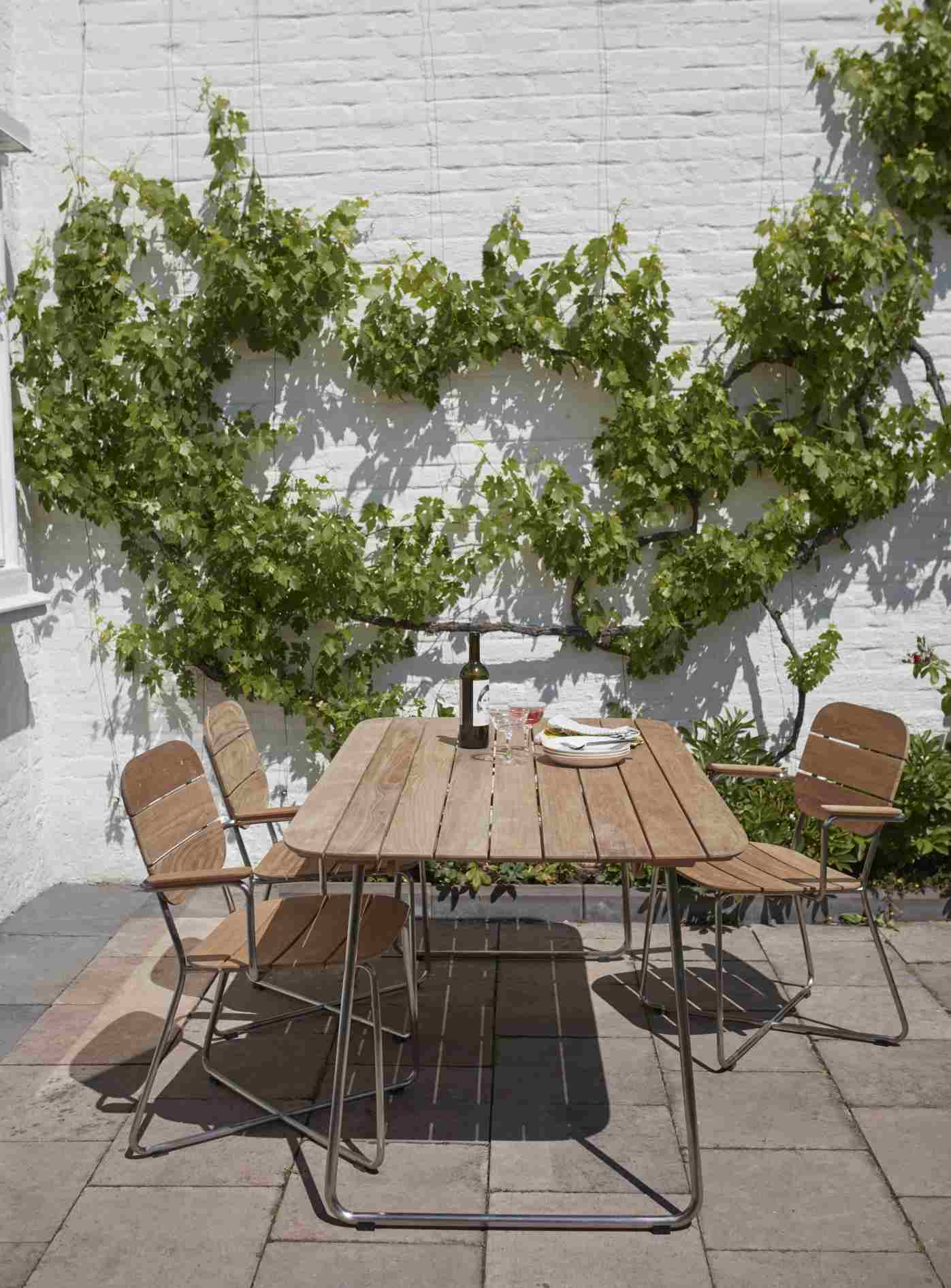 Lilium Table Esstisch von Skagerak by Fritz Hansen im Garten mit Stühlen und Dekoration.