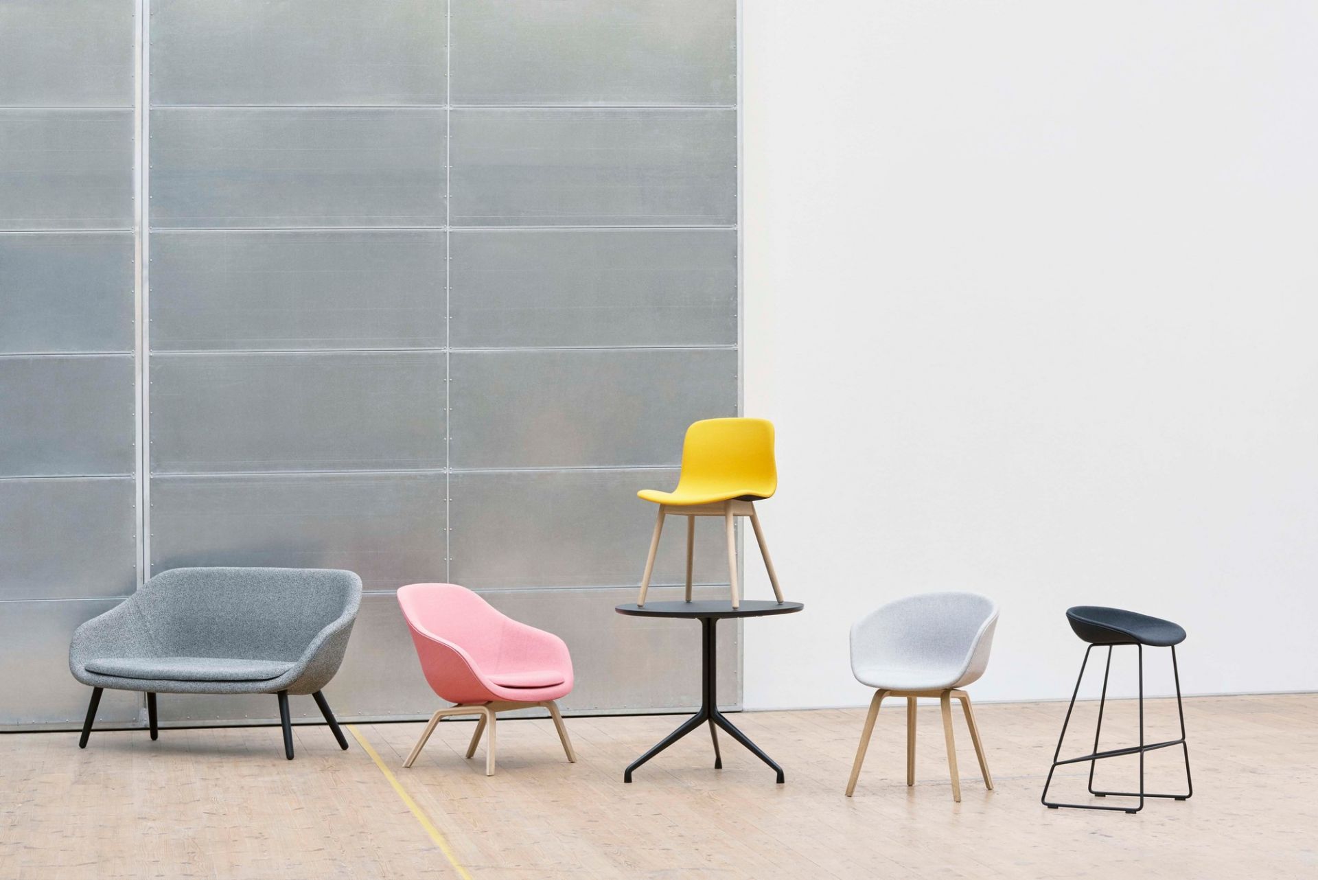 Verschiedene Hay About A Chair AAC 13 Stühle mit Vollpolster in Grau, Gelb, Rosa und Schwarz auf Holzboden.