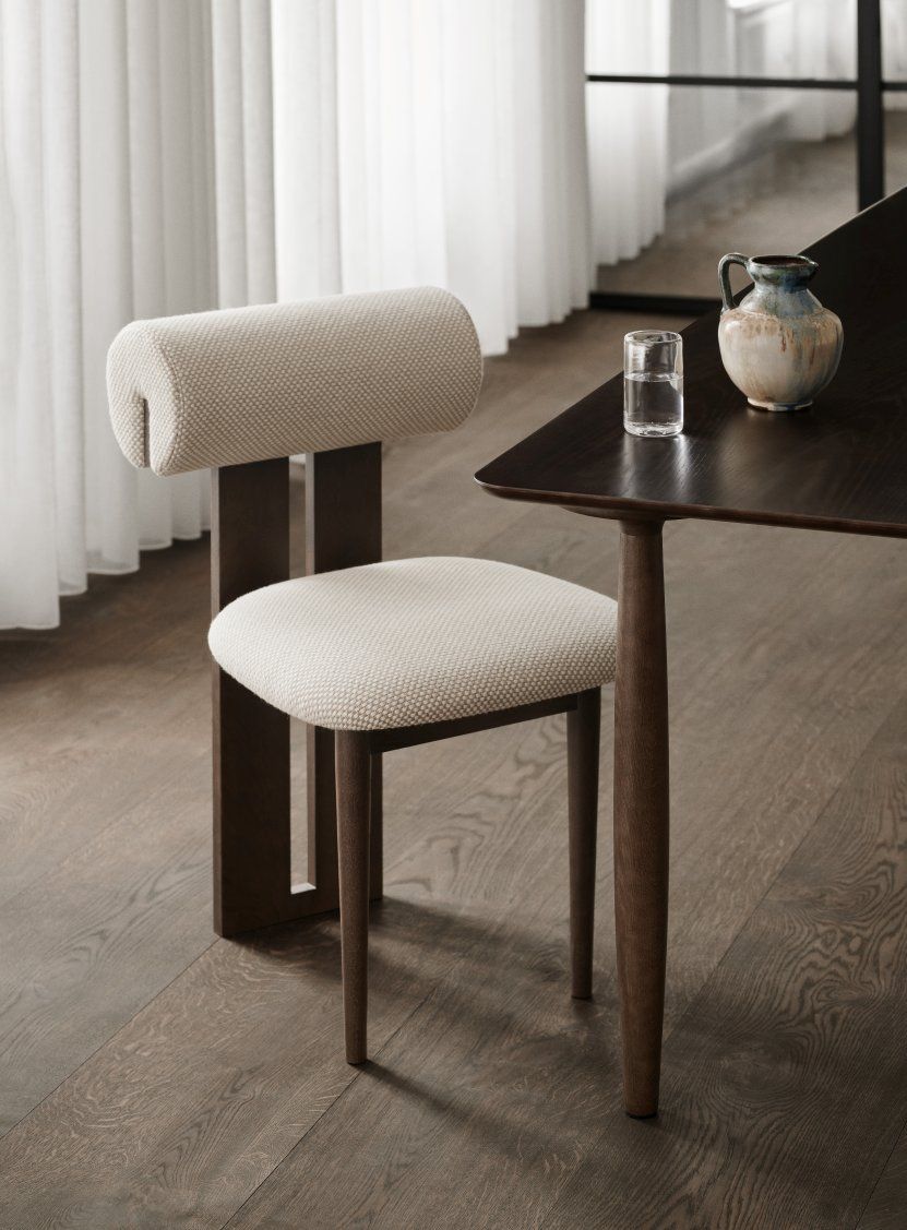 NORR11 Hippo Stuhl mit beigem Stoffbezug und dunklem Holzgestell am Esstisch.