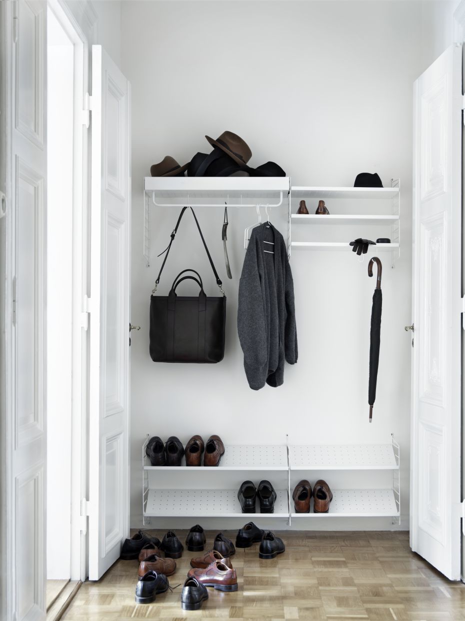 Flur mit String Regalsystem: Stangen, Regalböden und Accessoires wie Schuhe, Taschen und Kleidung.