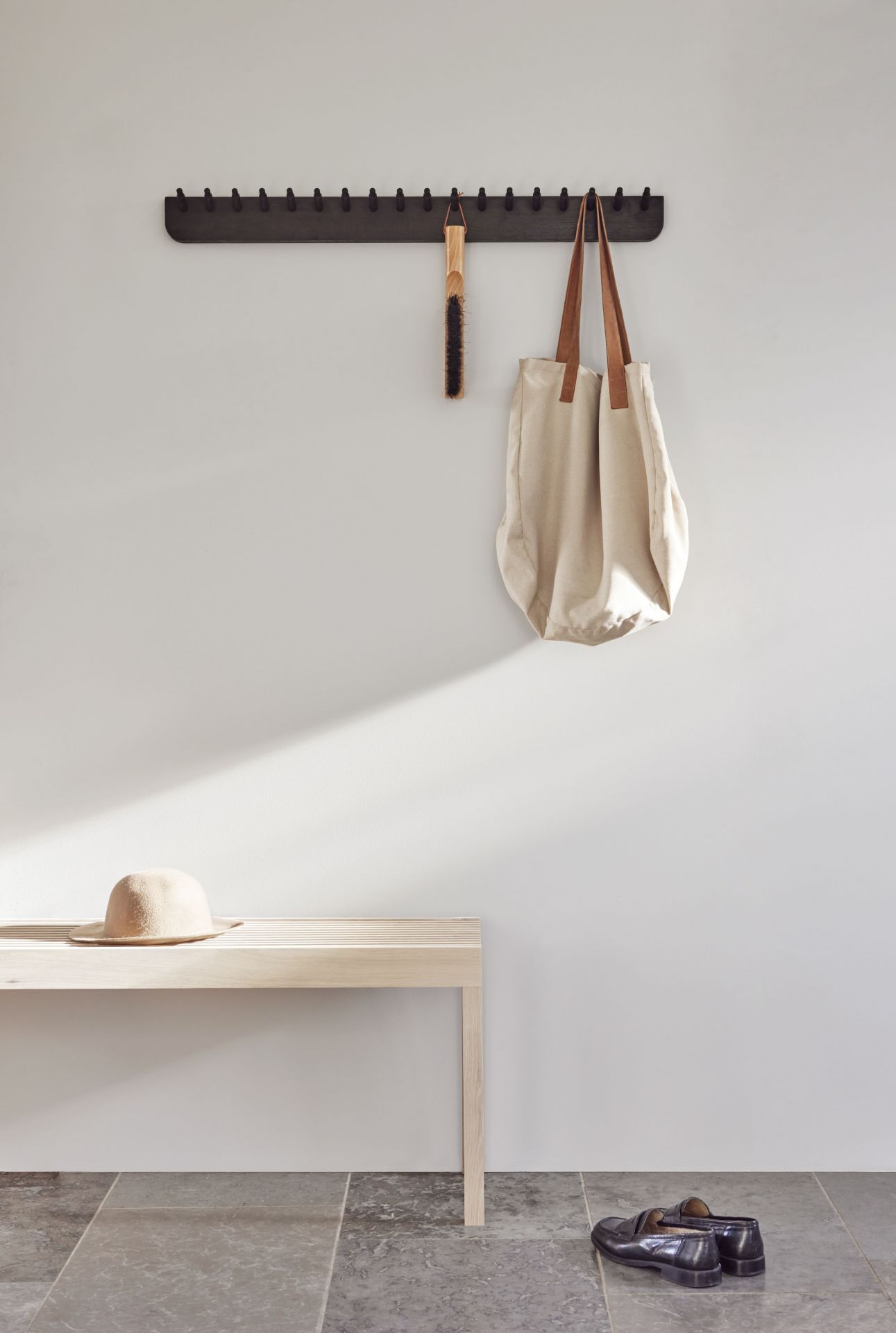 Echo Garderobenleiste von Form & Refine aus Eiche mit Tasche, Bürste und Hut im Flur.