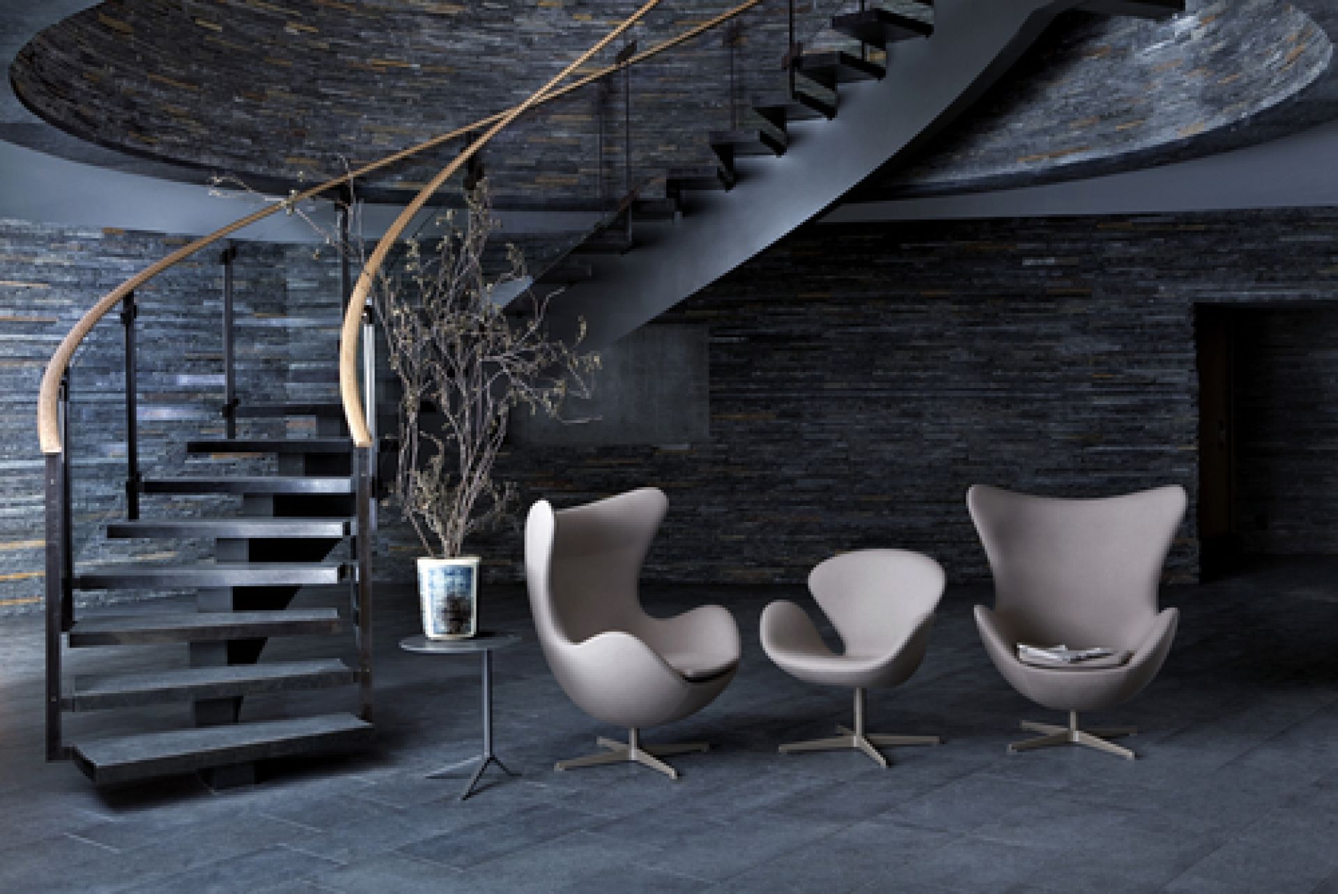 Drei graue Fritz Hansen Schwan Sessel in modernem Raum mit Steintreppe und Dekoration.