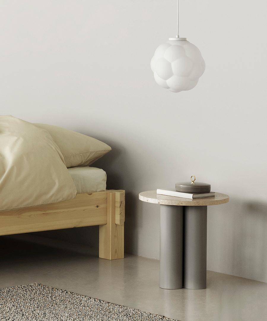 Normann Copenhagen Dit Coffee Table Beistelltisch im Schlafzimmer, runde Tischplatte aus Travertin, graue zylindrische Beine.