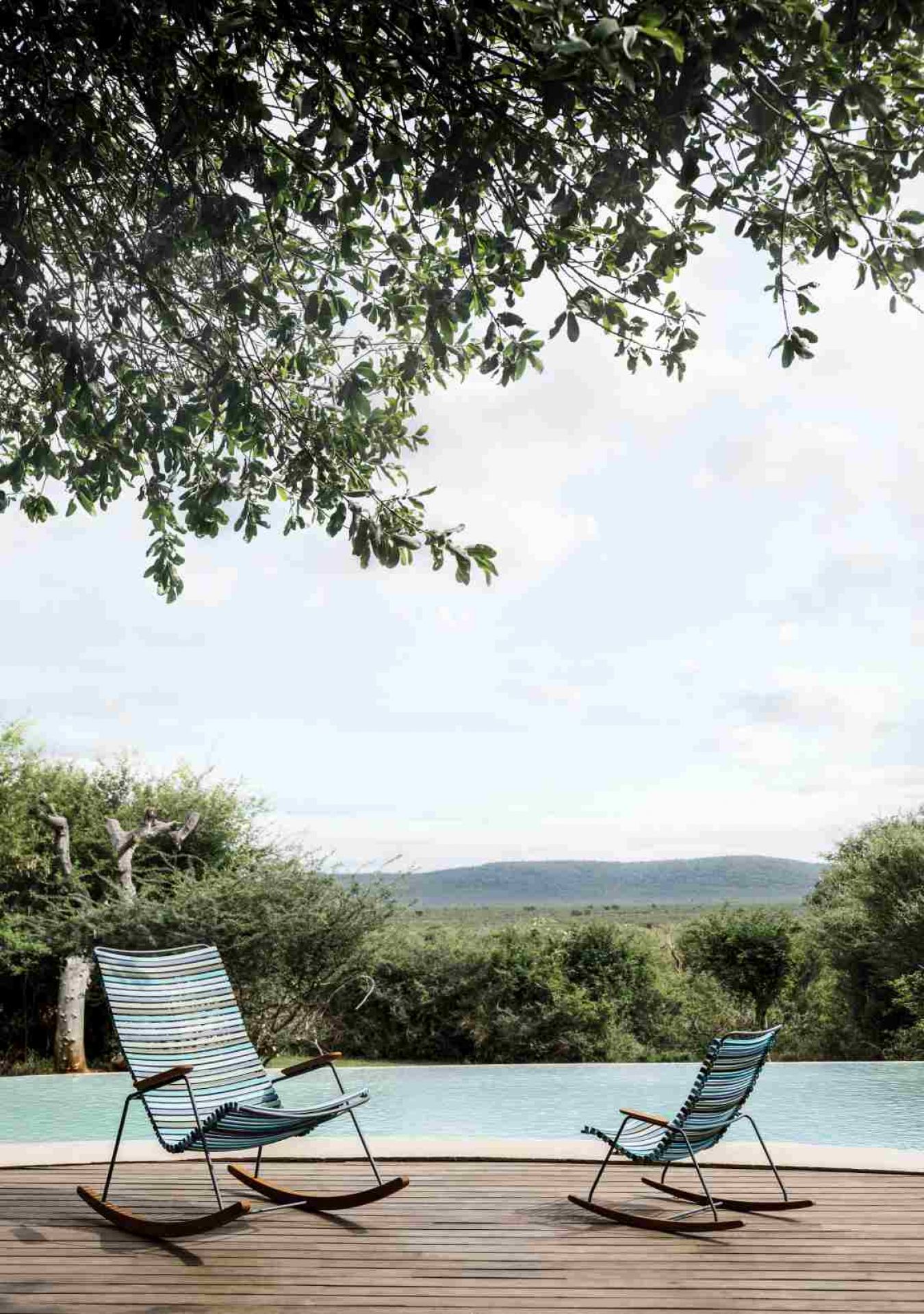 Zwei Click Schaukelstühle von Houe im Freien am Pool mit schöner Aussicht.