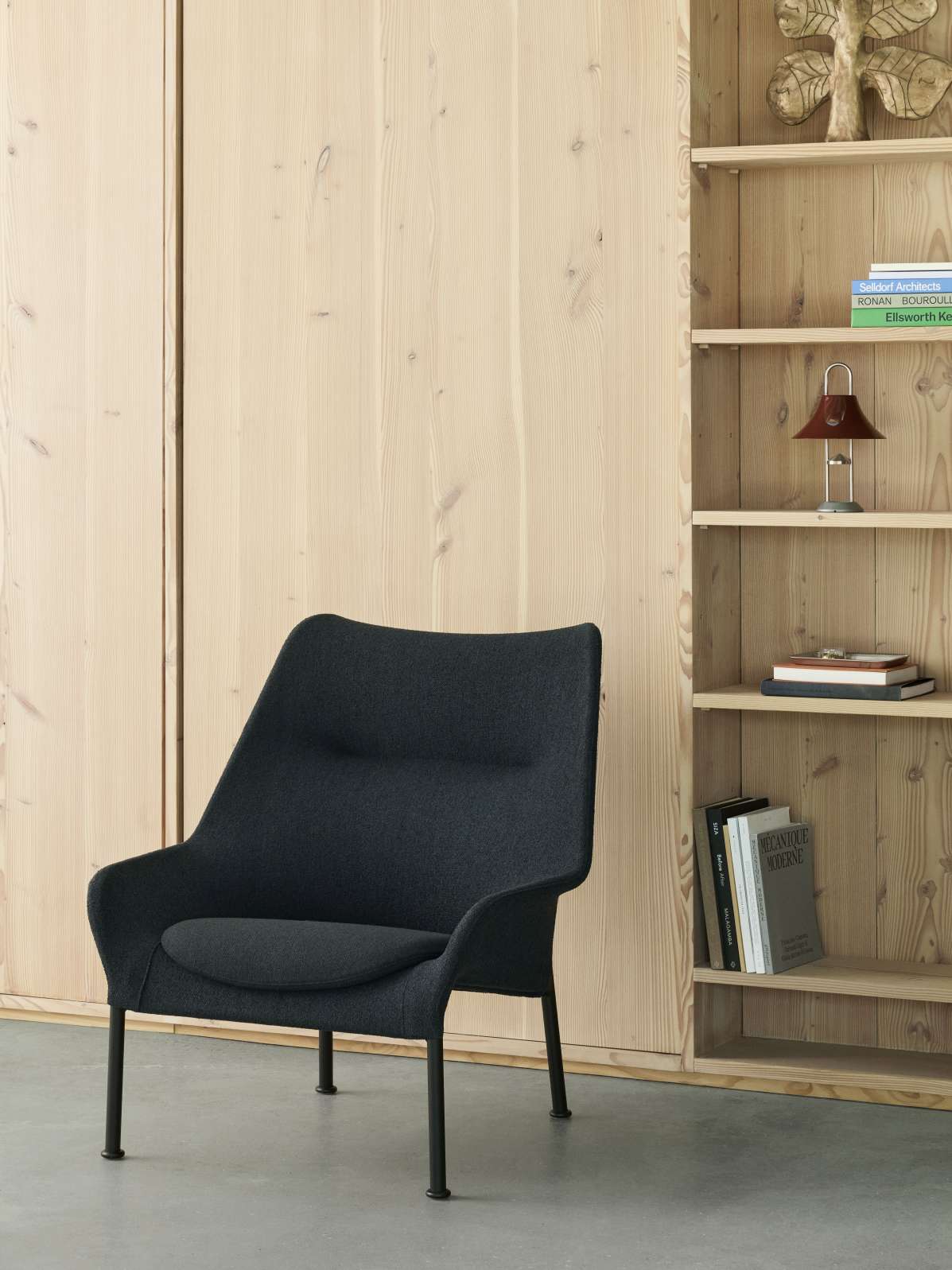 Hay 02 Lounge Chair Sessel in Anthrazit vor Holzregal, moderner skandinavischer Sessel für Wohnzimmer.