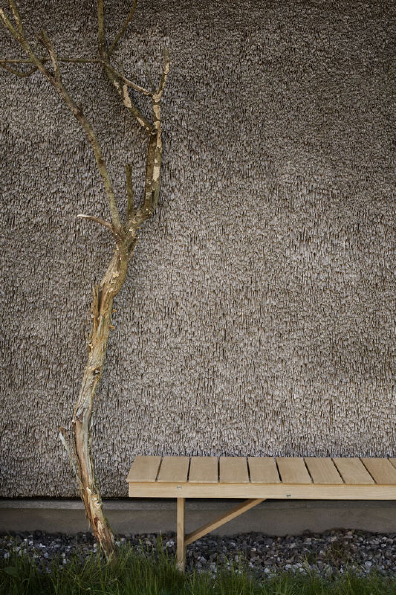 Mogensen Bank Outdoor von Carl Hansen & Søn vor Reetdach und Baum im Garten.