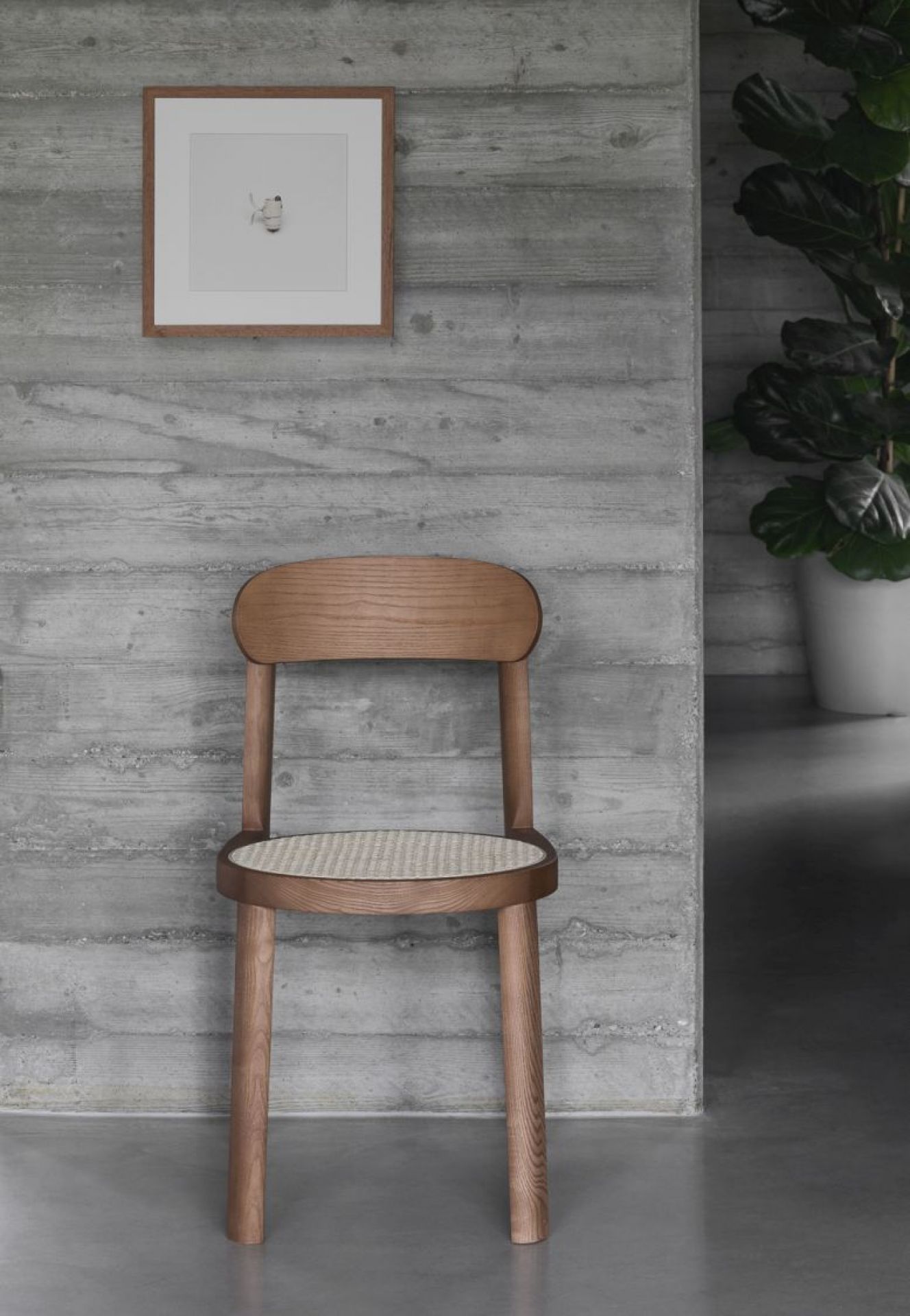 Brulla Stuhl von Miniforms, Esche schwarz gebeizt, mit Wiener Geflecht Sitzfläche vor Betonwand.